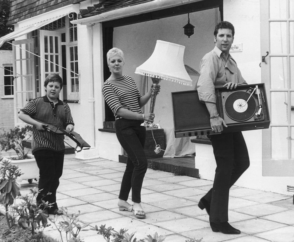 Tom Jones with Melinda Trenchard and their son, Mark, holding home appliances as they move into their new home on July 21, 1967, Sunbury, Surrey. / Source: Getty Images