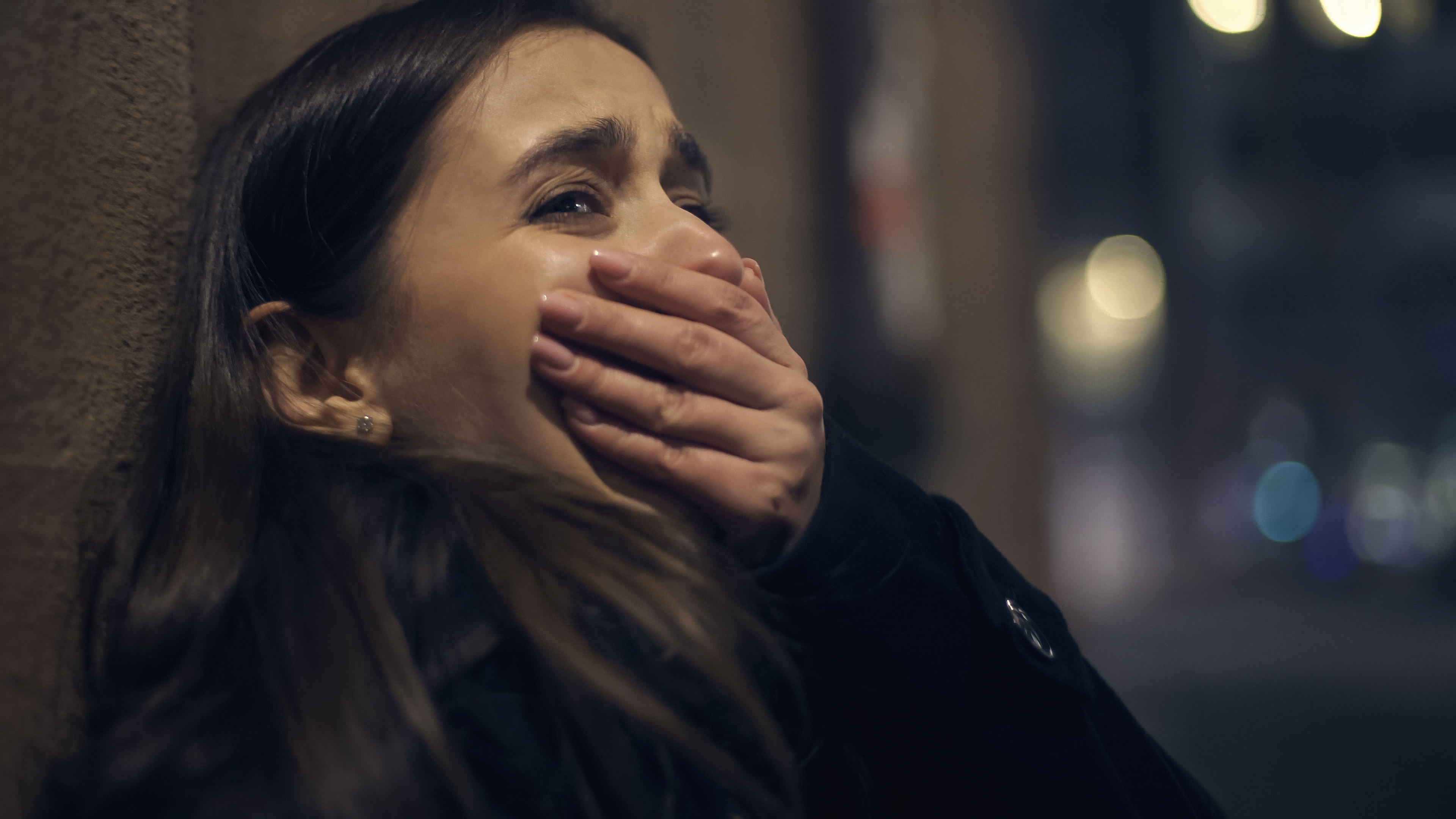 A scared woman crying with her hand clasped over her mouth | Source: Shutterstock