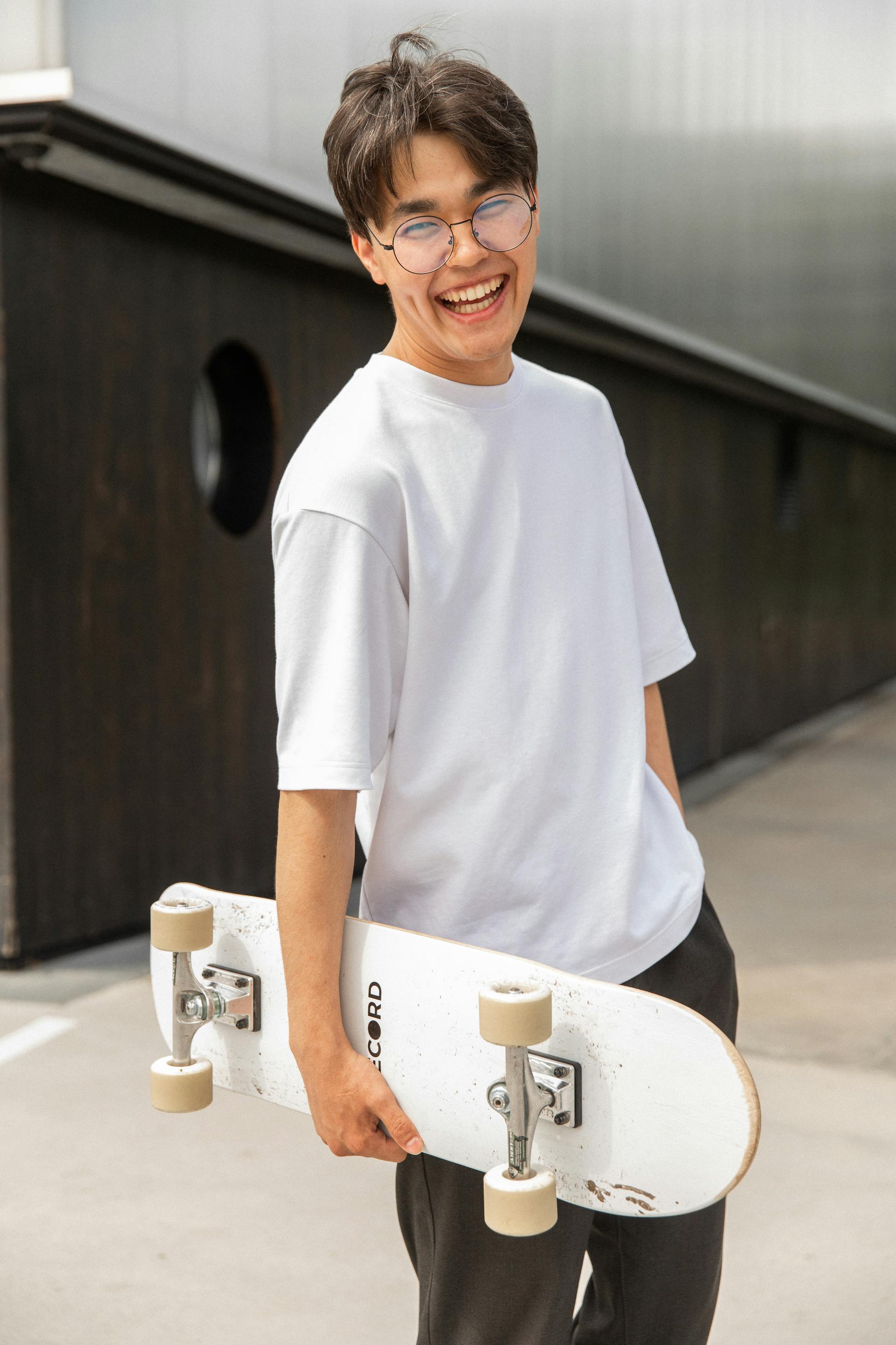 A young man holding a skateboard and laughing | Source: Pexels