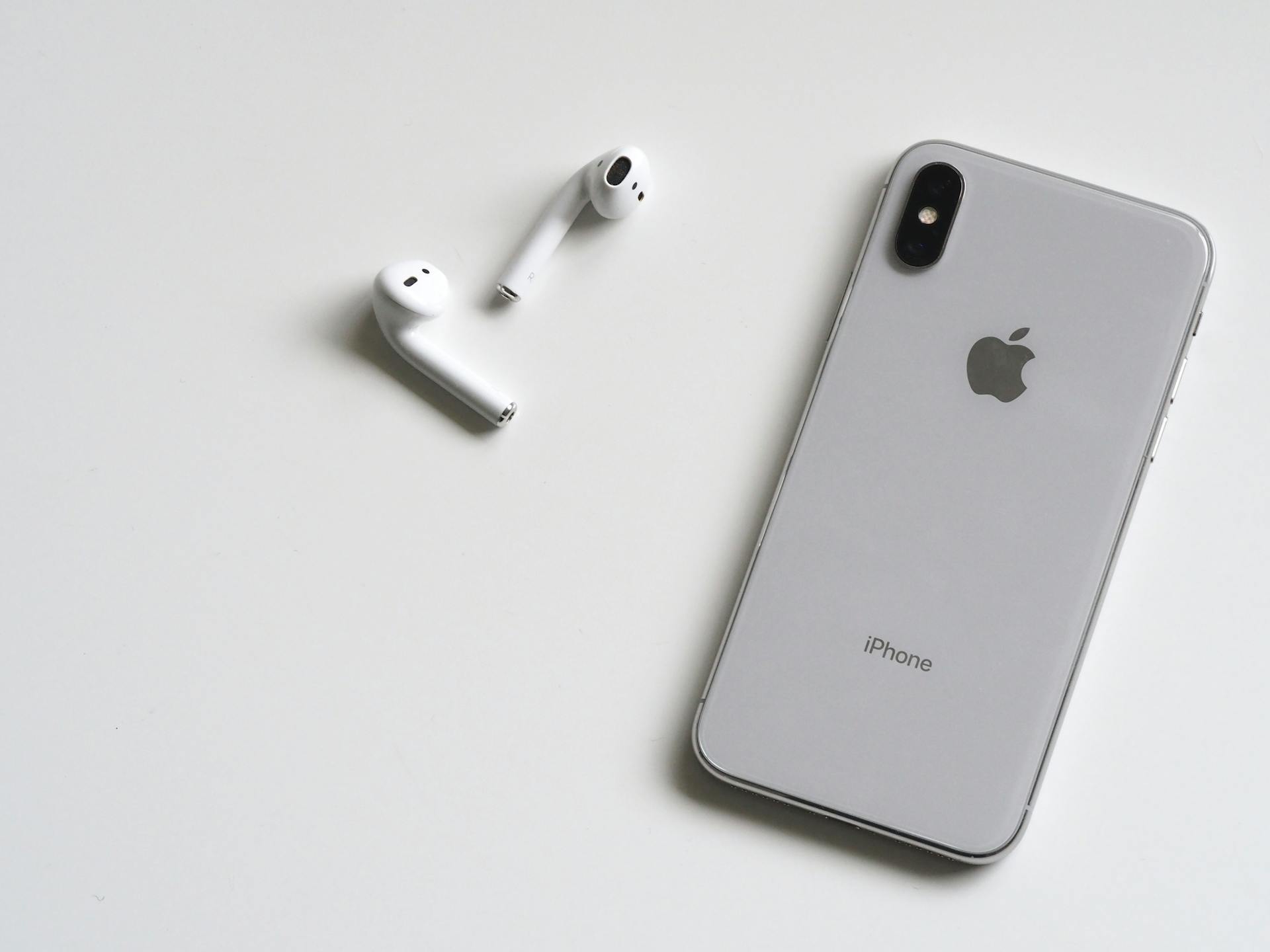 A silver iPhone X with Airpods | Source: Pexels