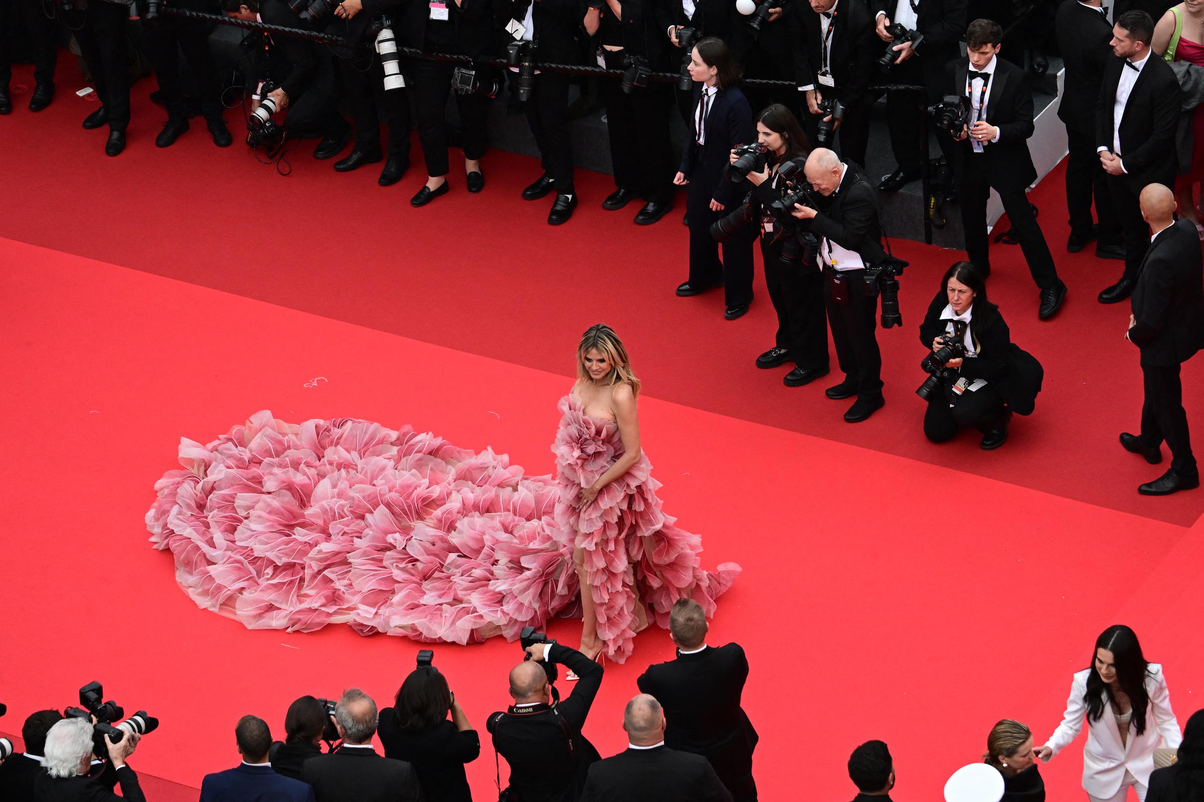 The moment feels cinematic—Klum stands at the center of the red carpet, striking a pose as photographers surround her, each one eager to capture her from every angle in all her breathtaking glory.