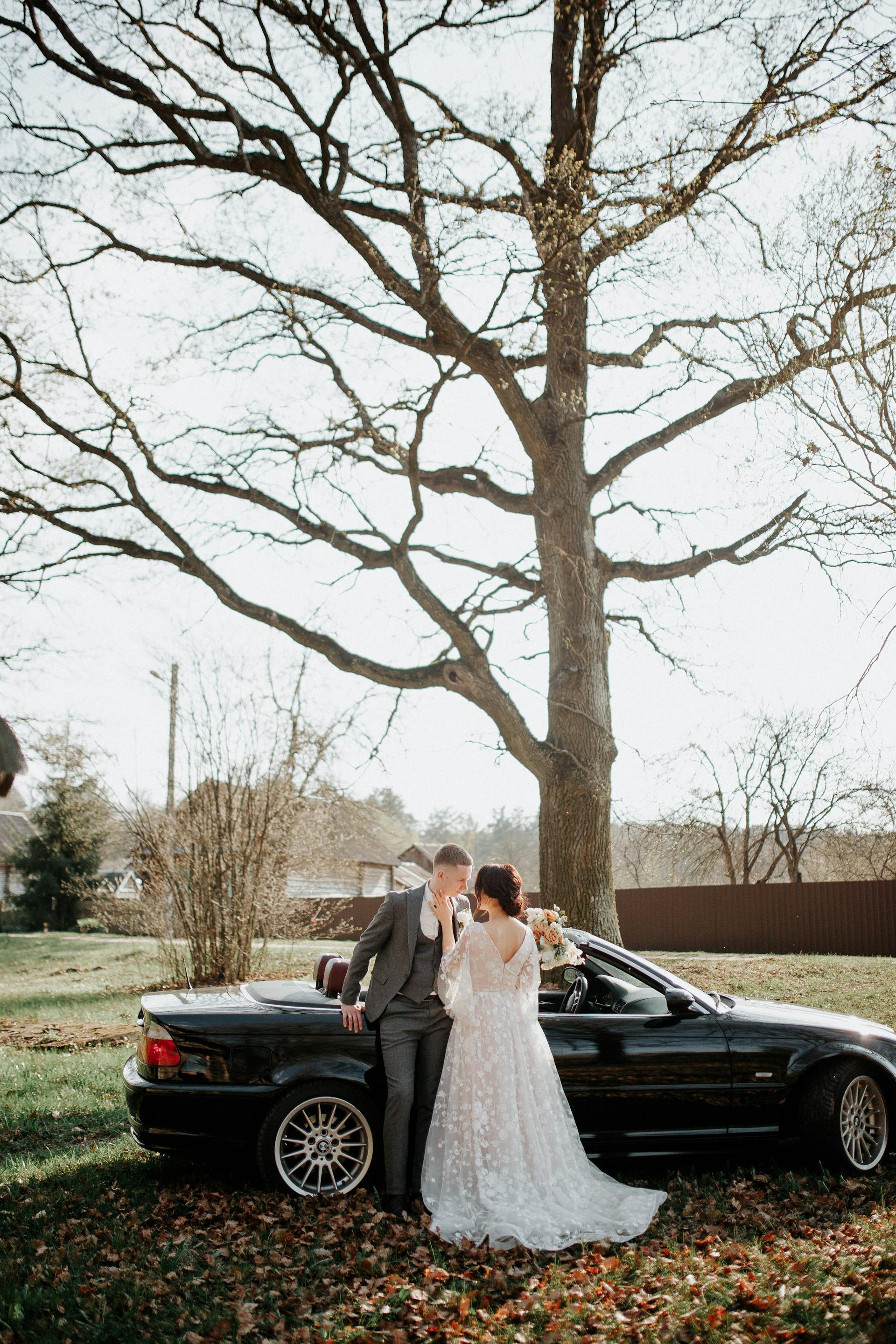 A bride and groom standing next to a car | Source: Pexels