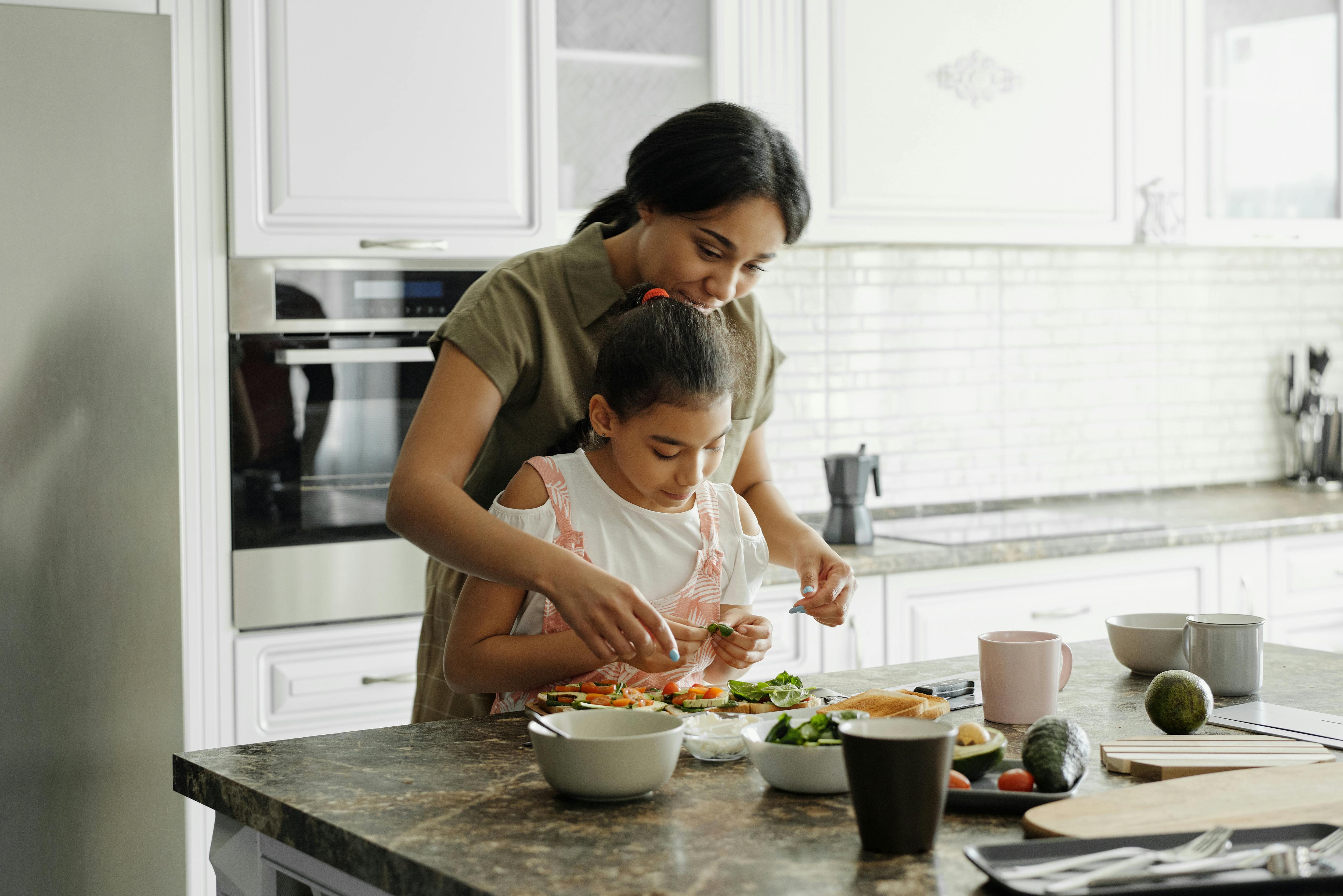 A little girl being taught how to cook by her mother | Source: Pexels