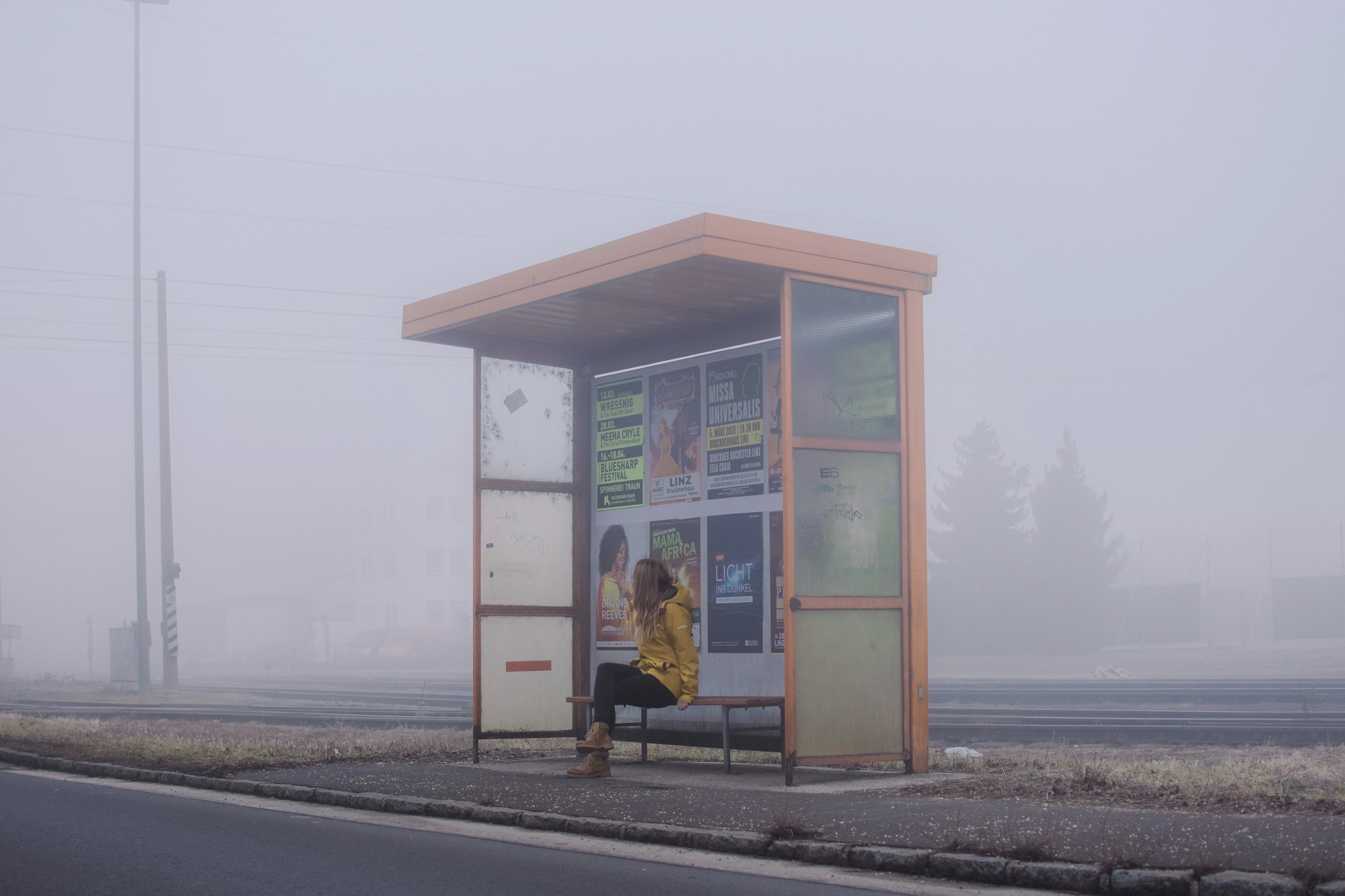 Mujer sentada en el banquillo de una parada de autobús. | Foto: Unsplash