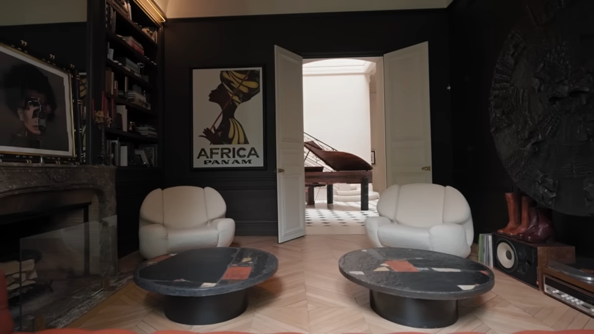 Looking toward the library's double doors, which open to reveal the grand entry hall and custom Steinway piano, decorated with a vintage "Africa Panam" travel poster. | Source: YouTube/@Archdigest