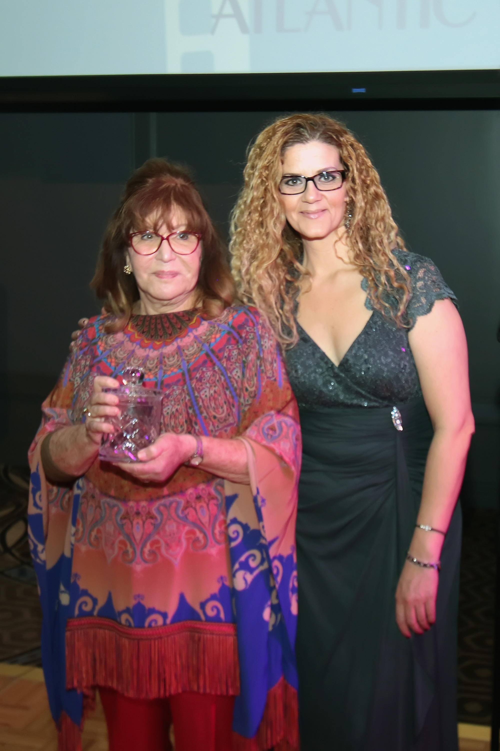 Sally Jessy Raphael poses with Executive Director Margaret Fontana during an award dinner at the Garden State Film Festival, held at Resorts Casino Hotel in Atlantic City, New Jersey, on April 2, 2017. Raphael, holding a crystal award, wears a vibrant fringe-trimmed top paired with her signature red glasses.