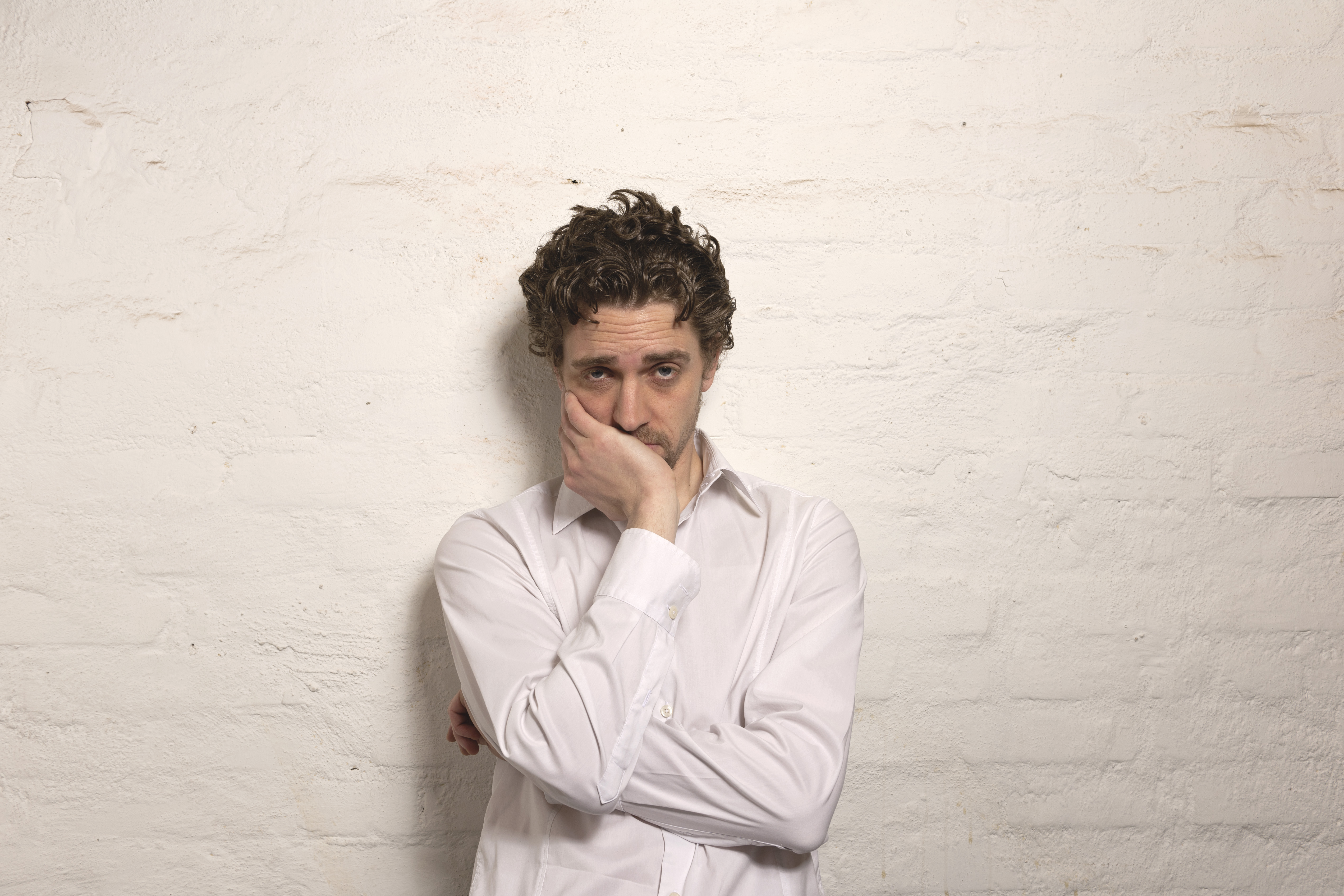 Germany, Hamburg, Mid adult man leaning against wall, portrait | Source: Getty Images