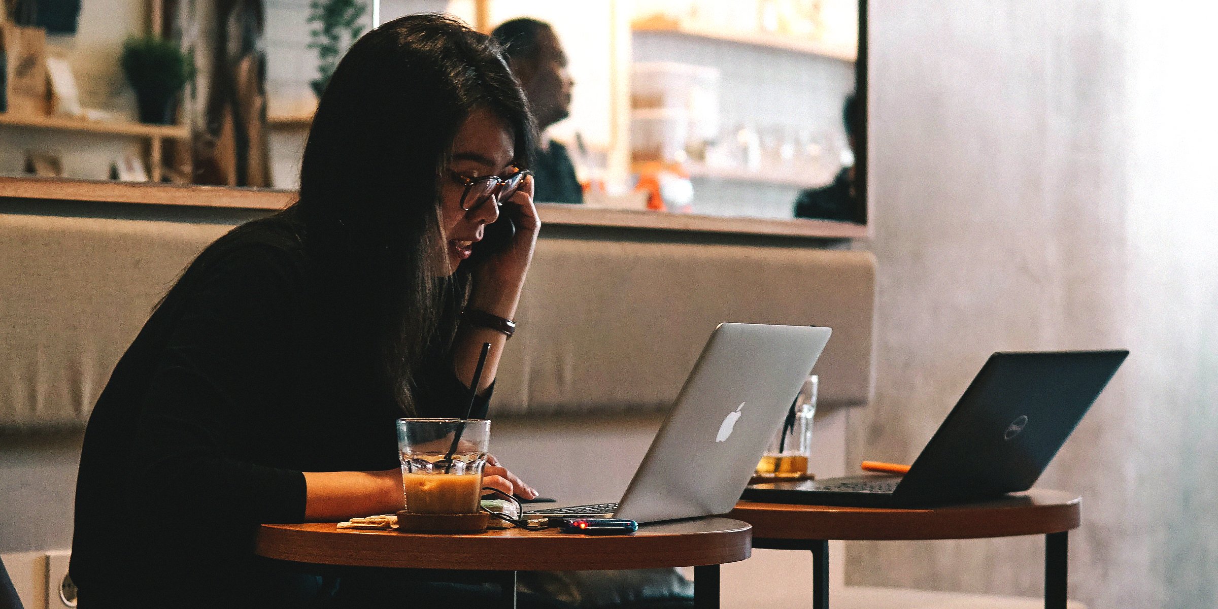 A lady on her phone and laptop in a restaurant | Source: Unsplash 