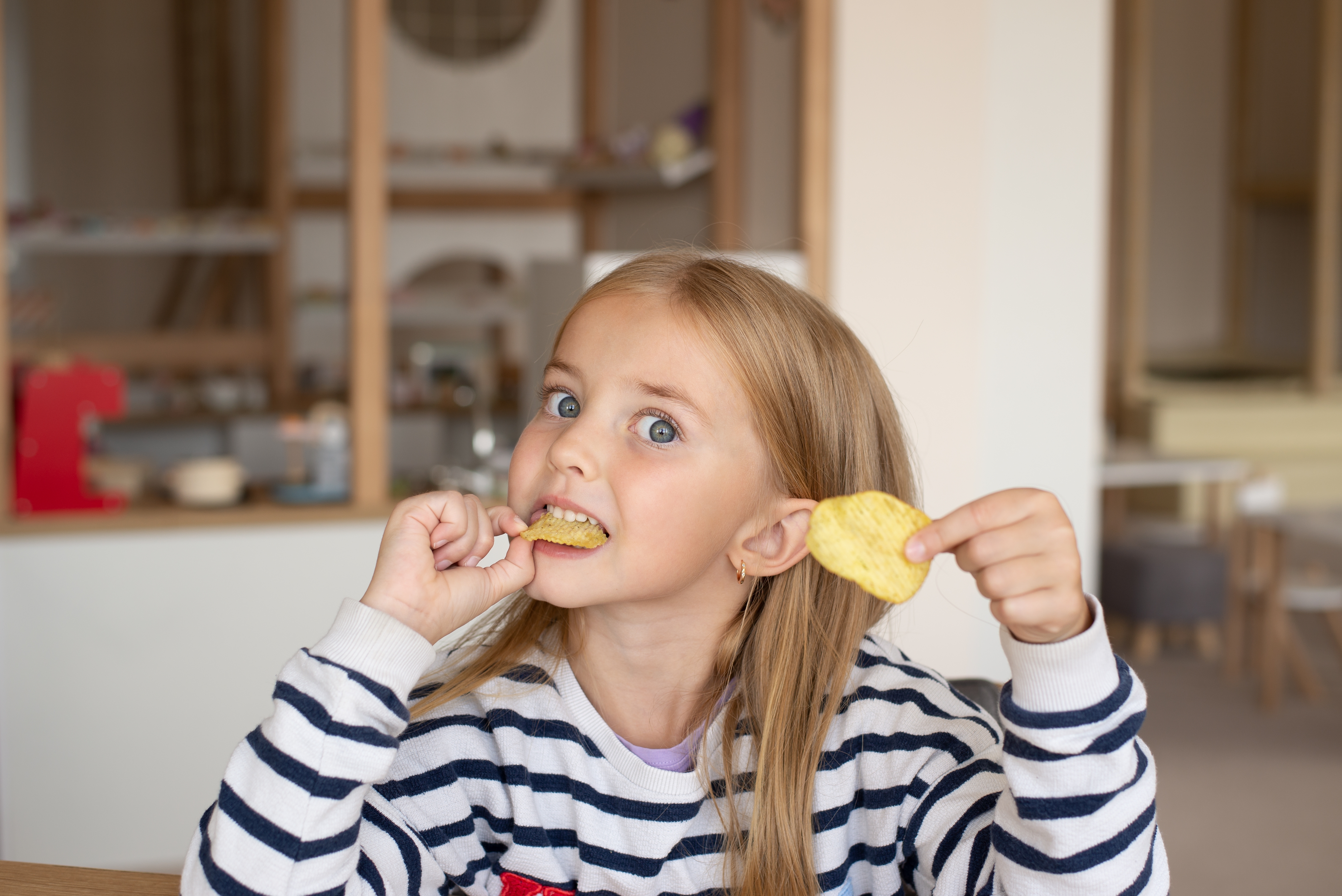 A little girl eating potato chips | Source: Shutterstock