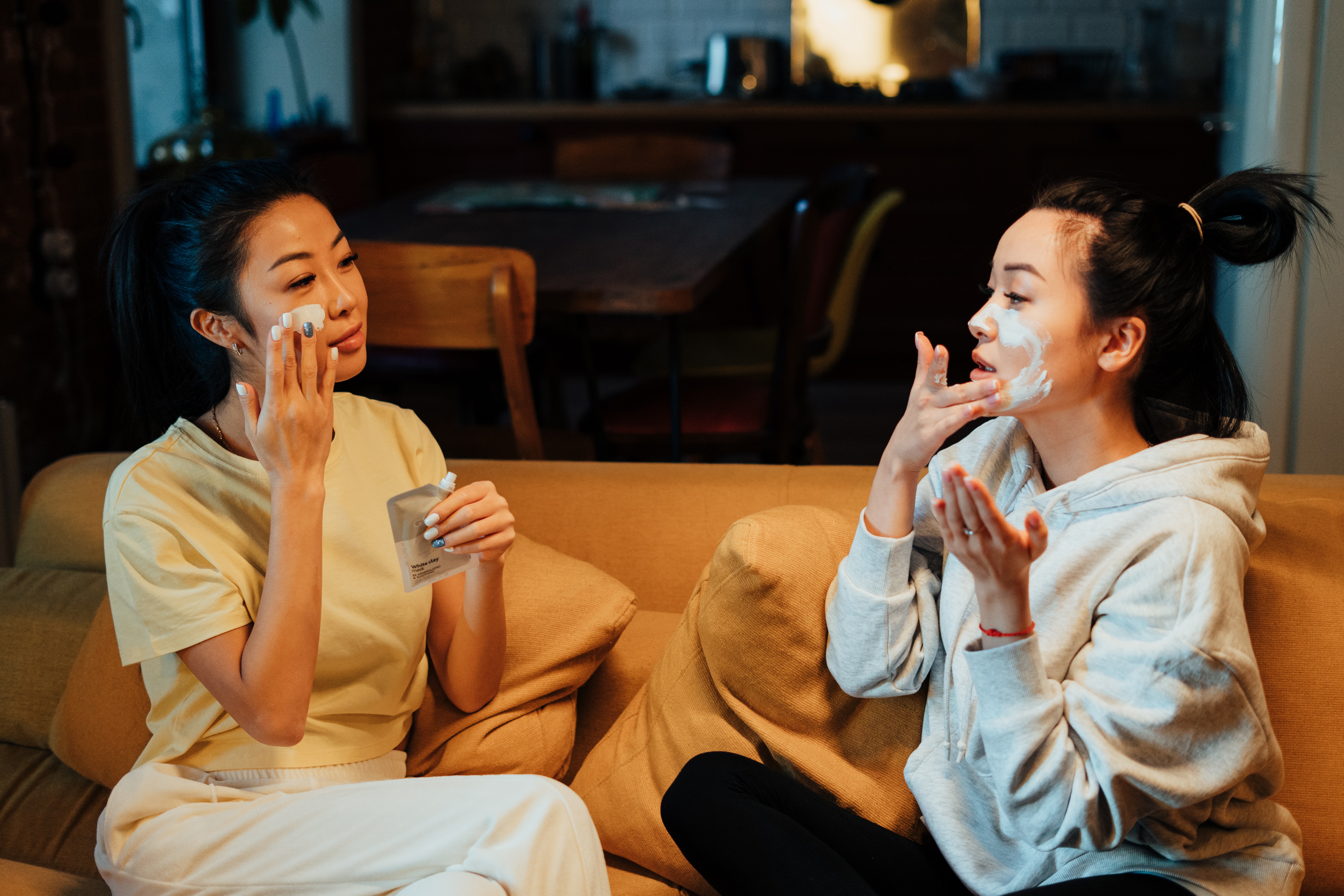 Two women applying face masksin a living room | Source: Pexels