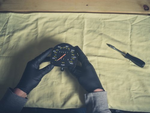 Man holding a speedometer and odometer with tools to make changes. | Source: Shutterstock.