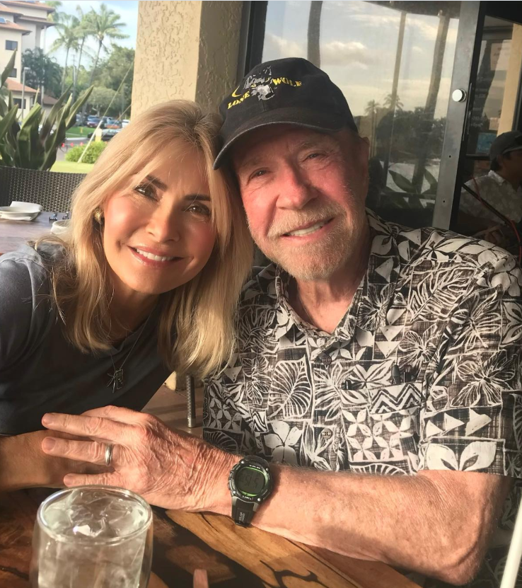 Chuck Norris smiles warmly beside his wife as they sit together outdoors, the soft Hawaiian light and palm-lined backdrop adding to the peaceful moment. | Source: Instagram/chucknorris