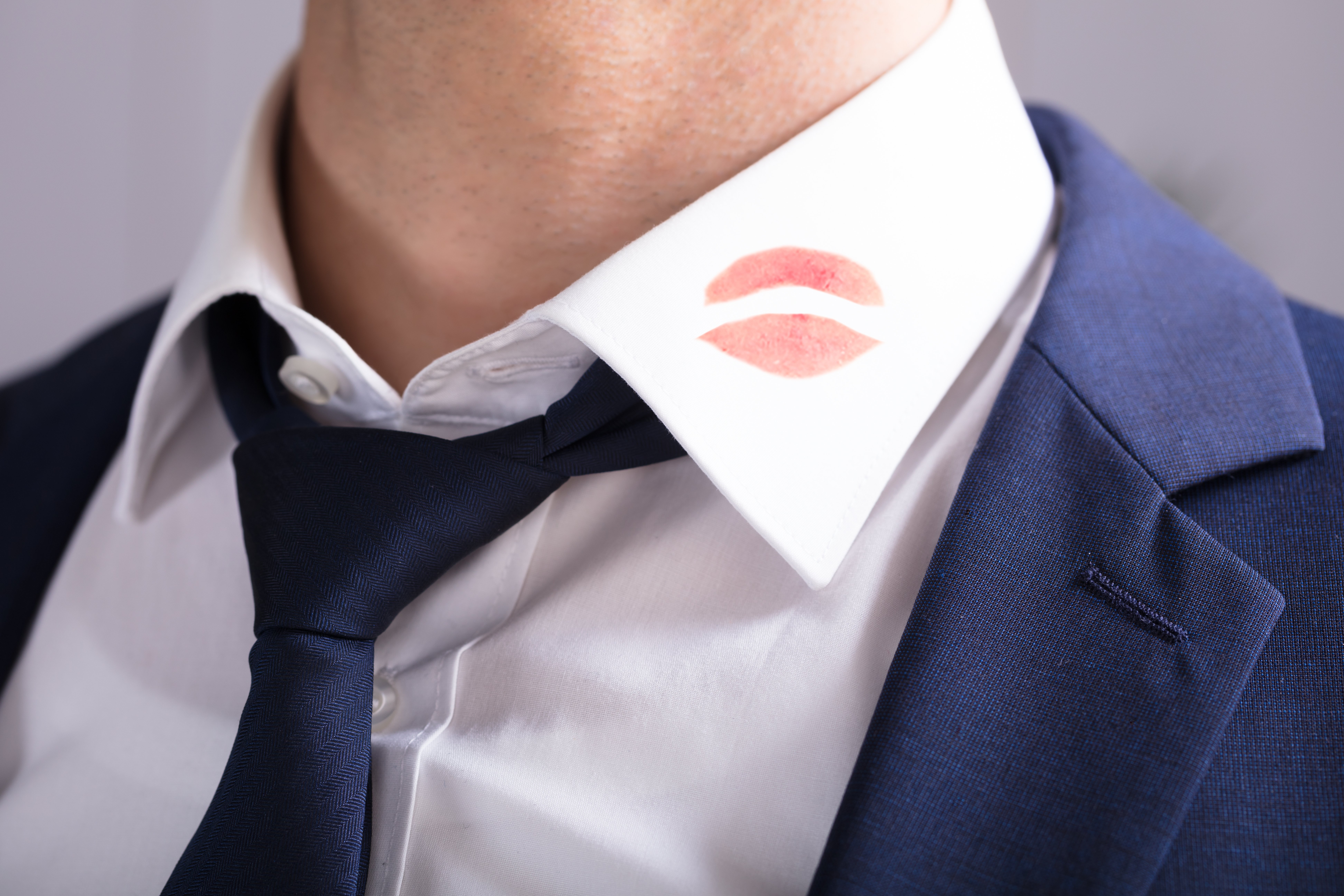 Hombre con camisa de cuello marcada con un beso en labial. | Fuente: Shutterstock