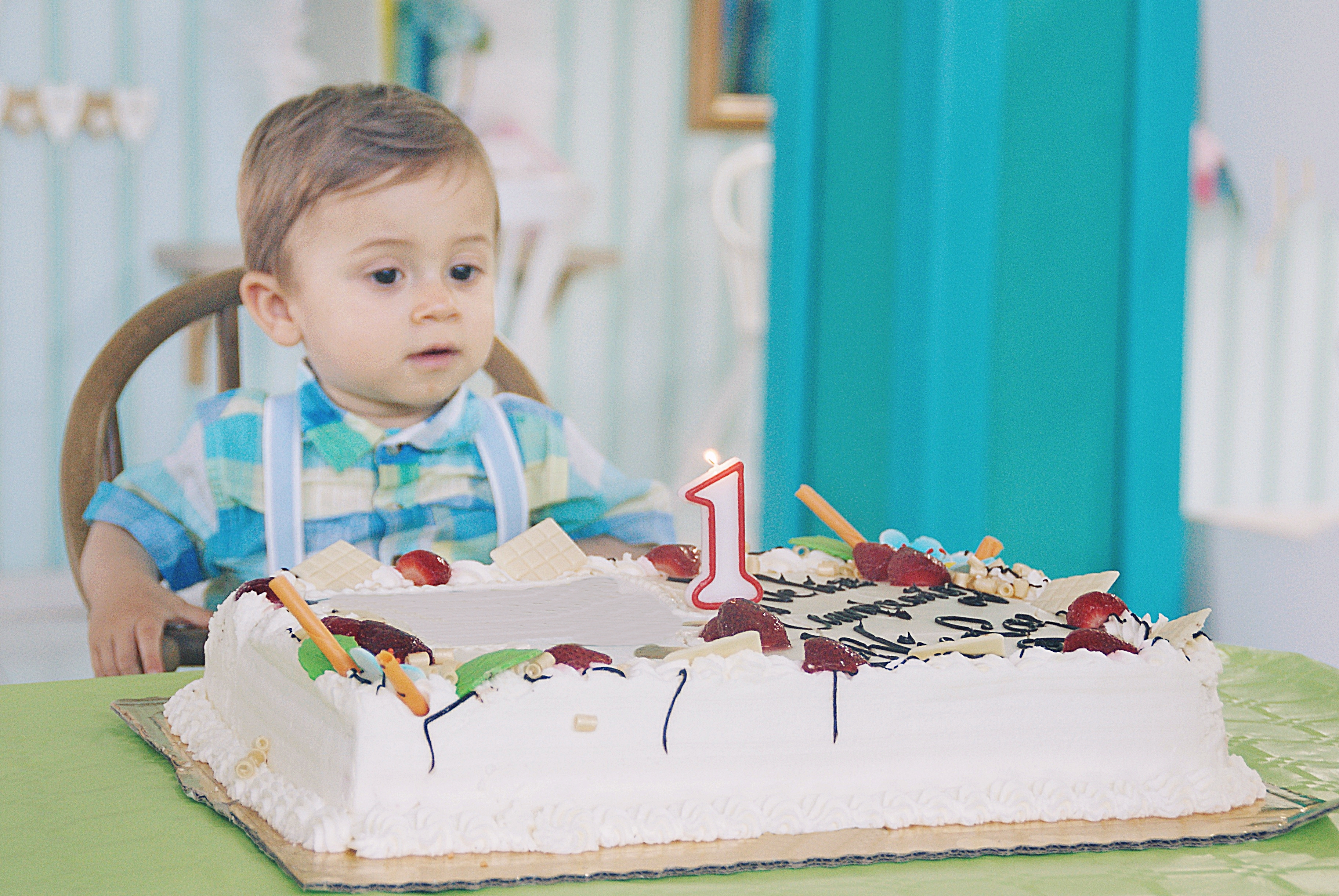 Portrait of a toddler sitting at a table ready to blow out a candle on his birthday cake | Source: Getty Images