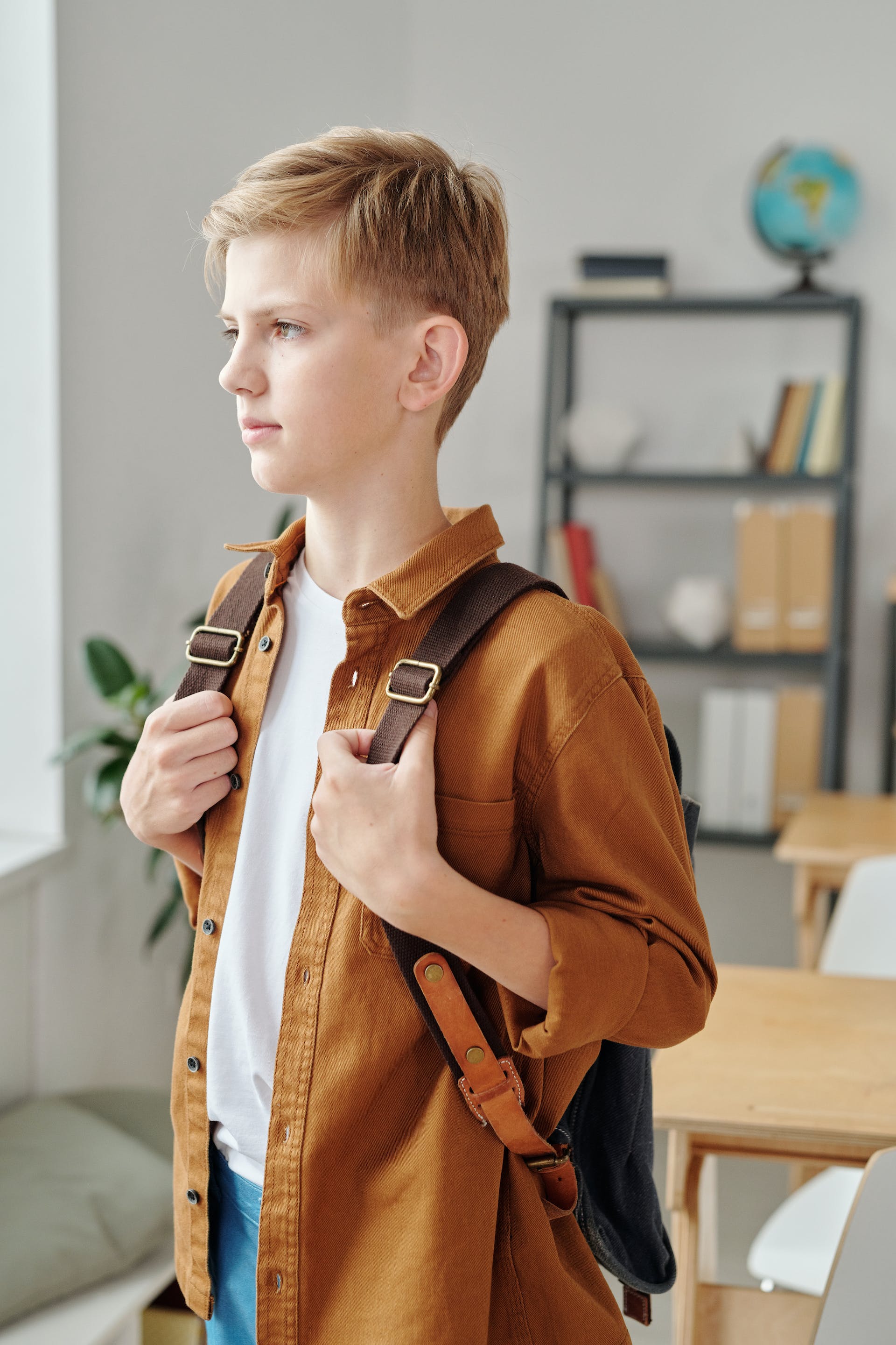 A sad young boy carrying a backpack | Source: Pexels