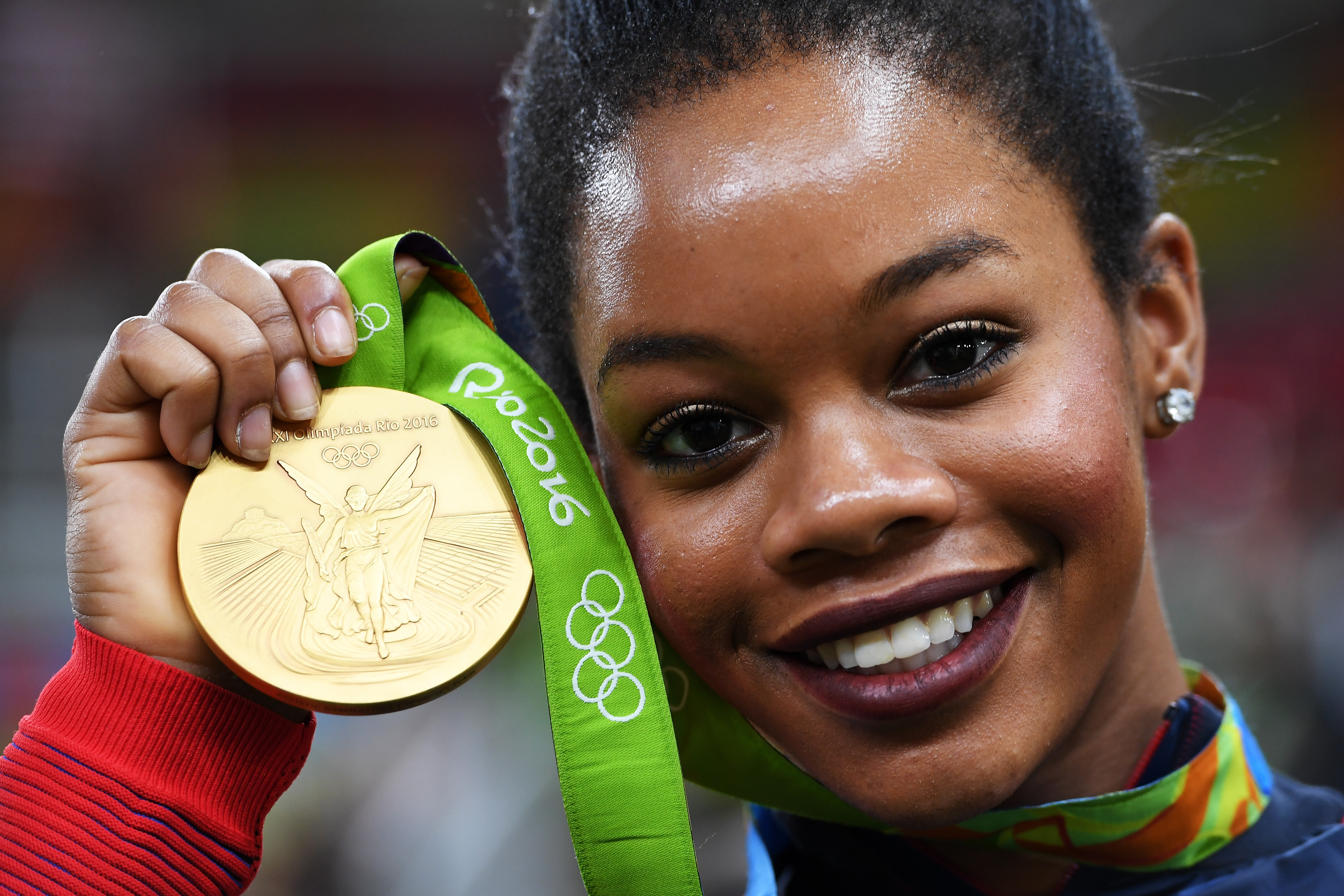 Gabrielle Douglas of the United States poses for photographs with her gold medal after the medal ceremony for the Artistic Gymnastics Women's Team on Day 4 of the Rio 2016 Olympic Games at the Rio Olympic Arena on August 9, 2016 in Rio de Janeiro, Brazil. | Source: Getty Images