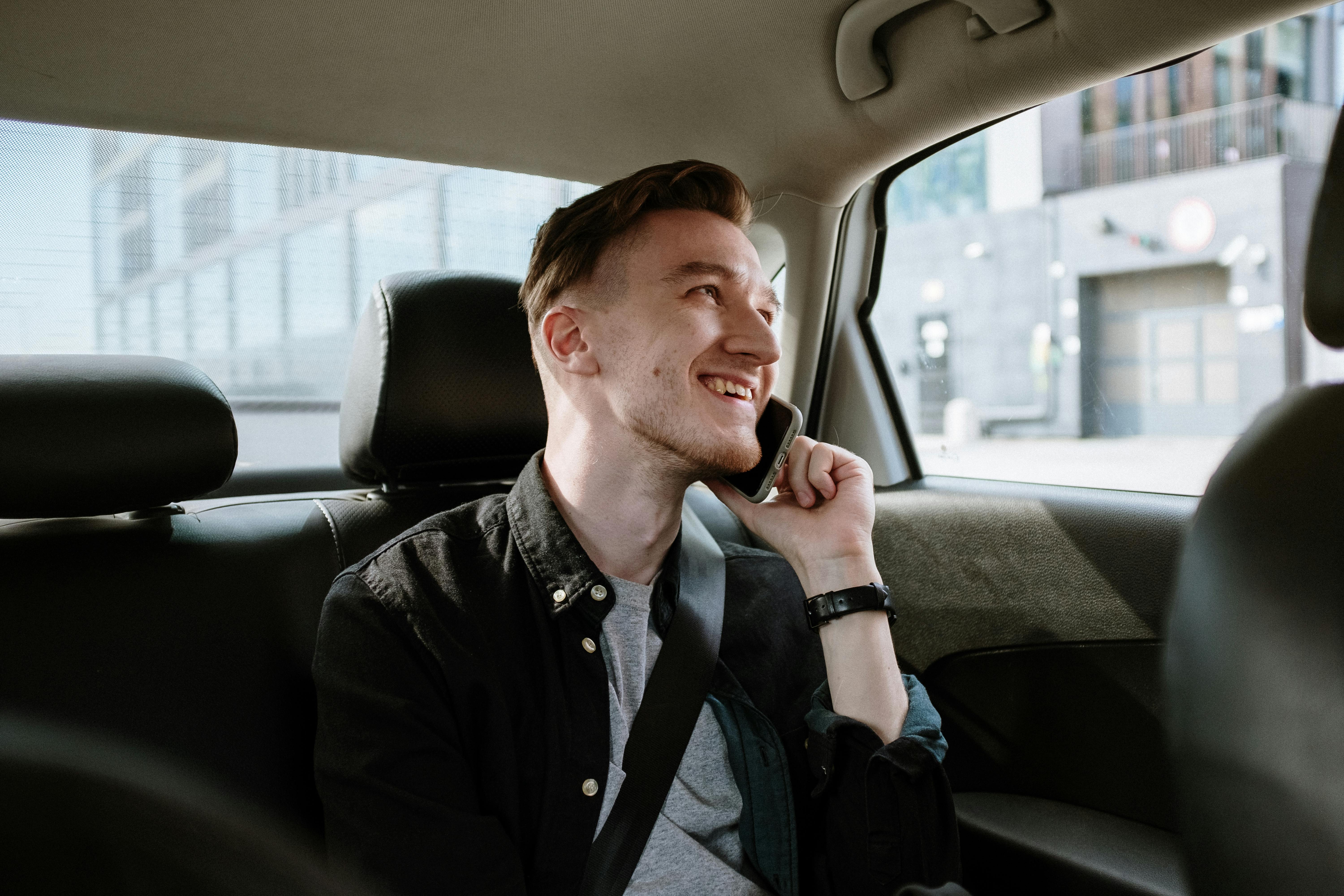 A happy man talking on a phone while riding in a car | Source: Pexels