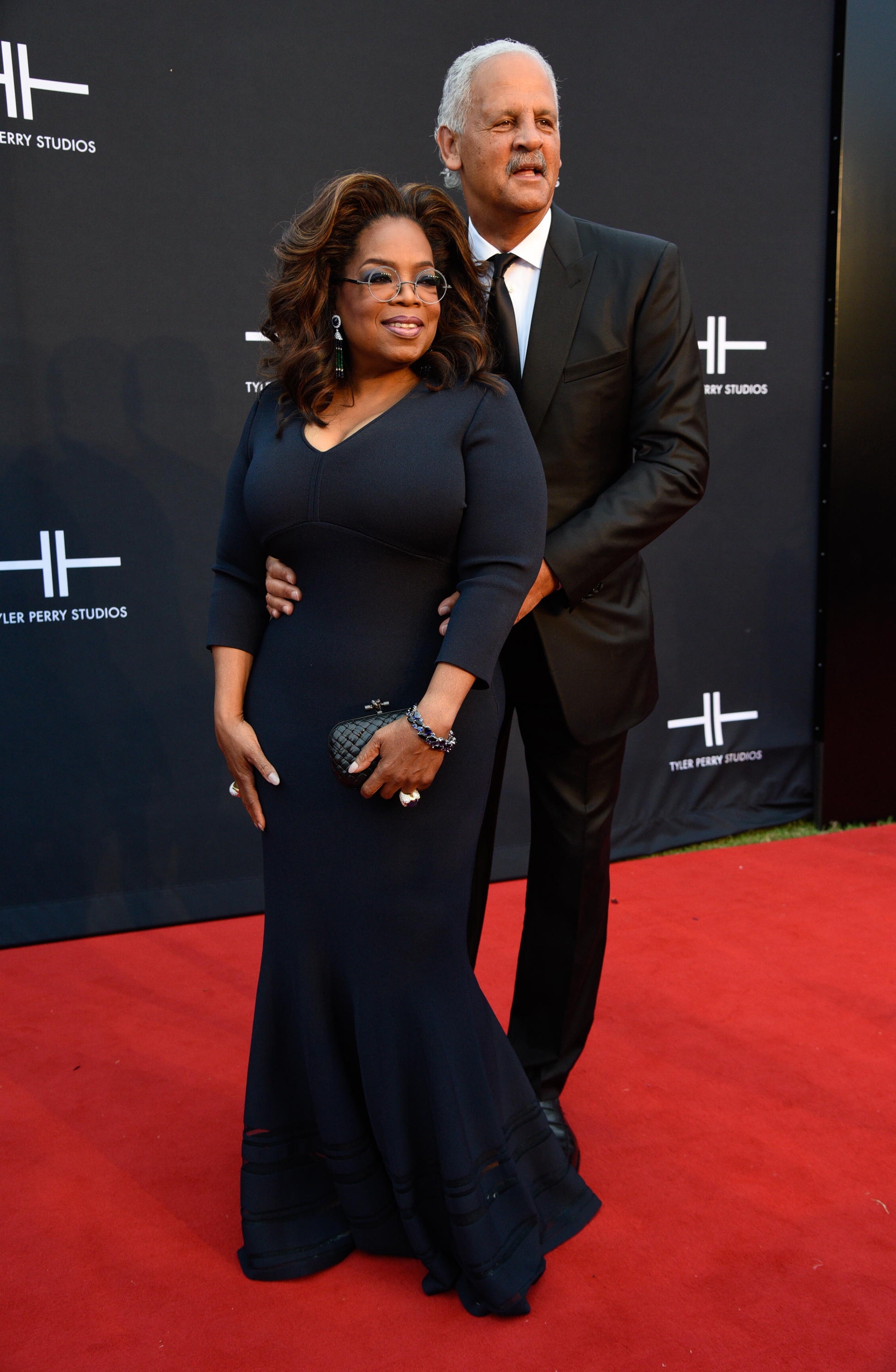 Winfrey posed in front of Graham on the red carpet at the Tyler Perry Studios Grand Opening Gala in Atlanta in 2019. She wore a long dark gown, while Graham stood behind her in a black suit and tie. | Source: Getty Images