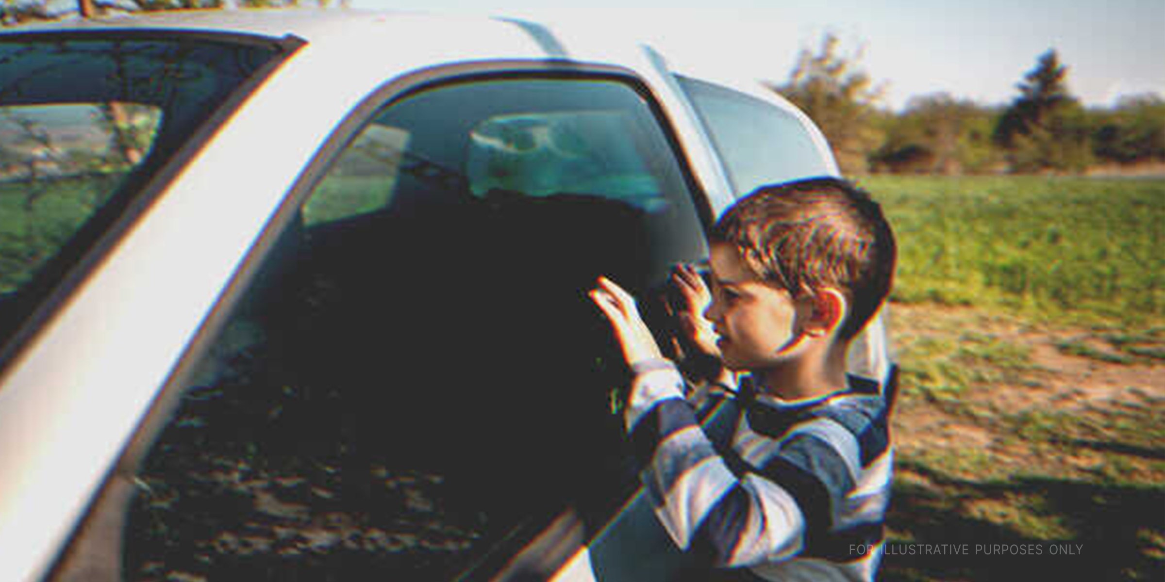 Little boy peeping into a car | Getty Images