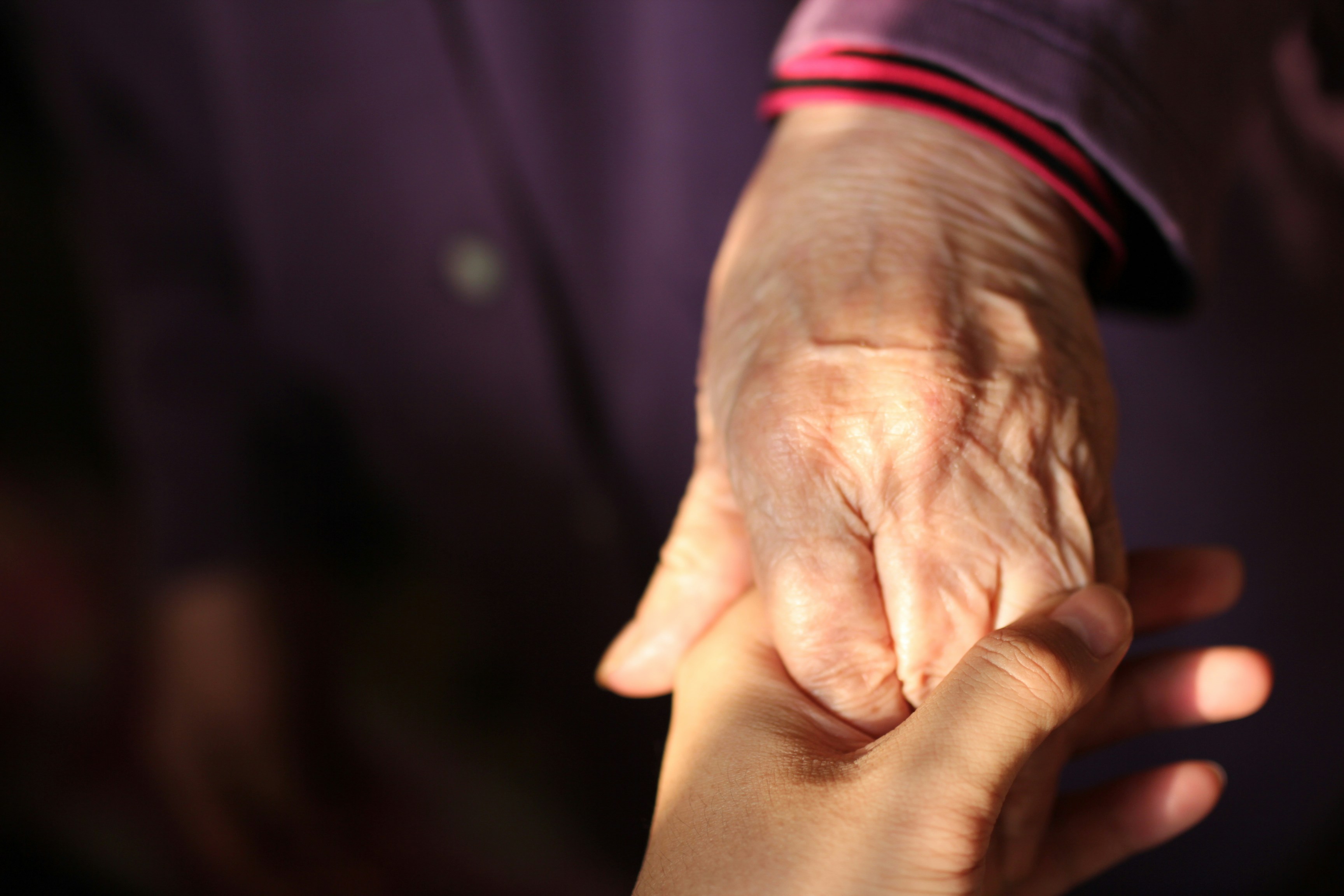 An older woman's hand holding a younger person's hand | Source: Unsplash