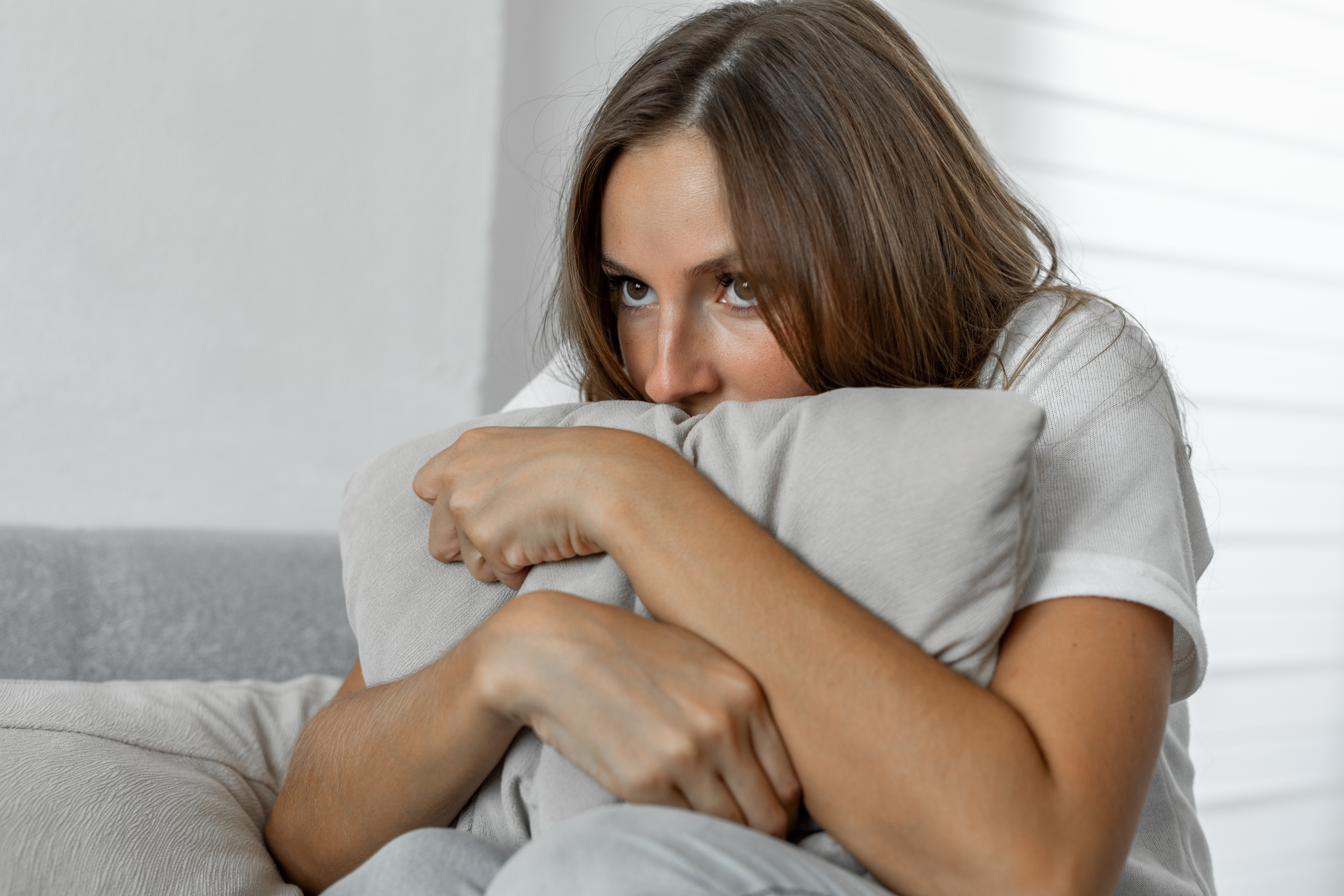 Scared woman at home embracing pillow sitting on a sofa | Source: Getty Images