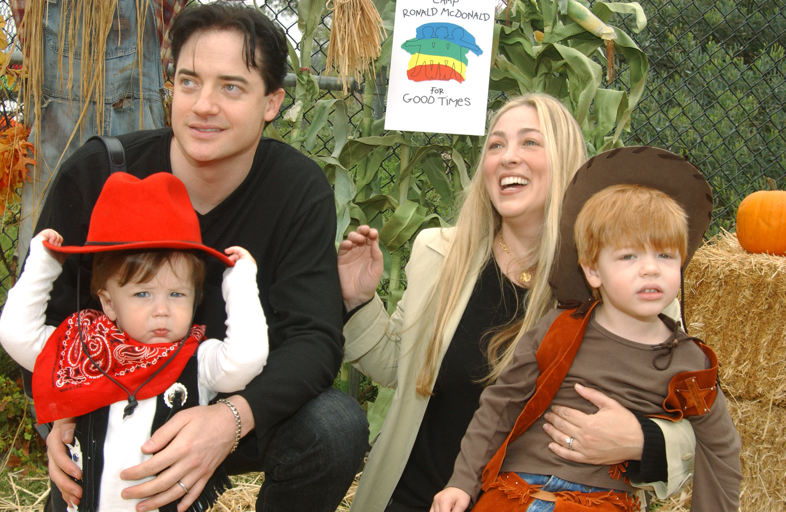 Brendan Fraser and Afton Smith smile with Leland Fraser and Griffin Arthur Fraser at Universal Studios for Camp Ronald McDonald for Good Times' 13th Annual Halloween Carnival, surrounded by pumpkins and hay.