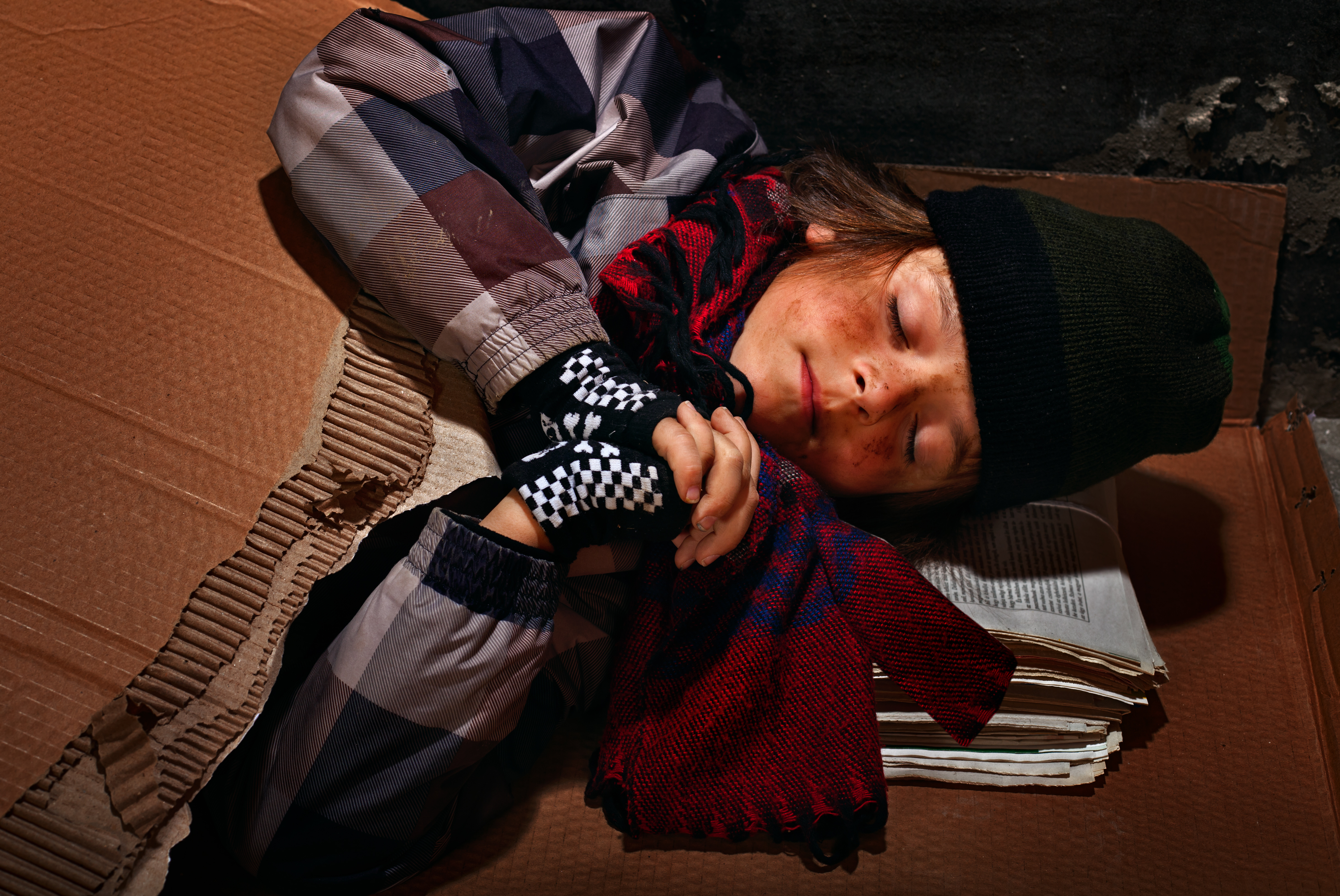 Poor beggar boy preparing to sleep on the street | Source: Shutterstock.com