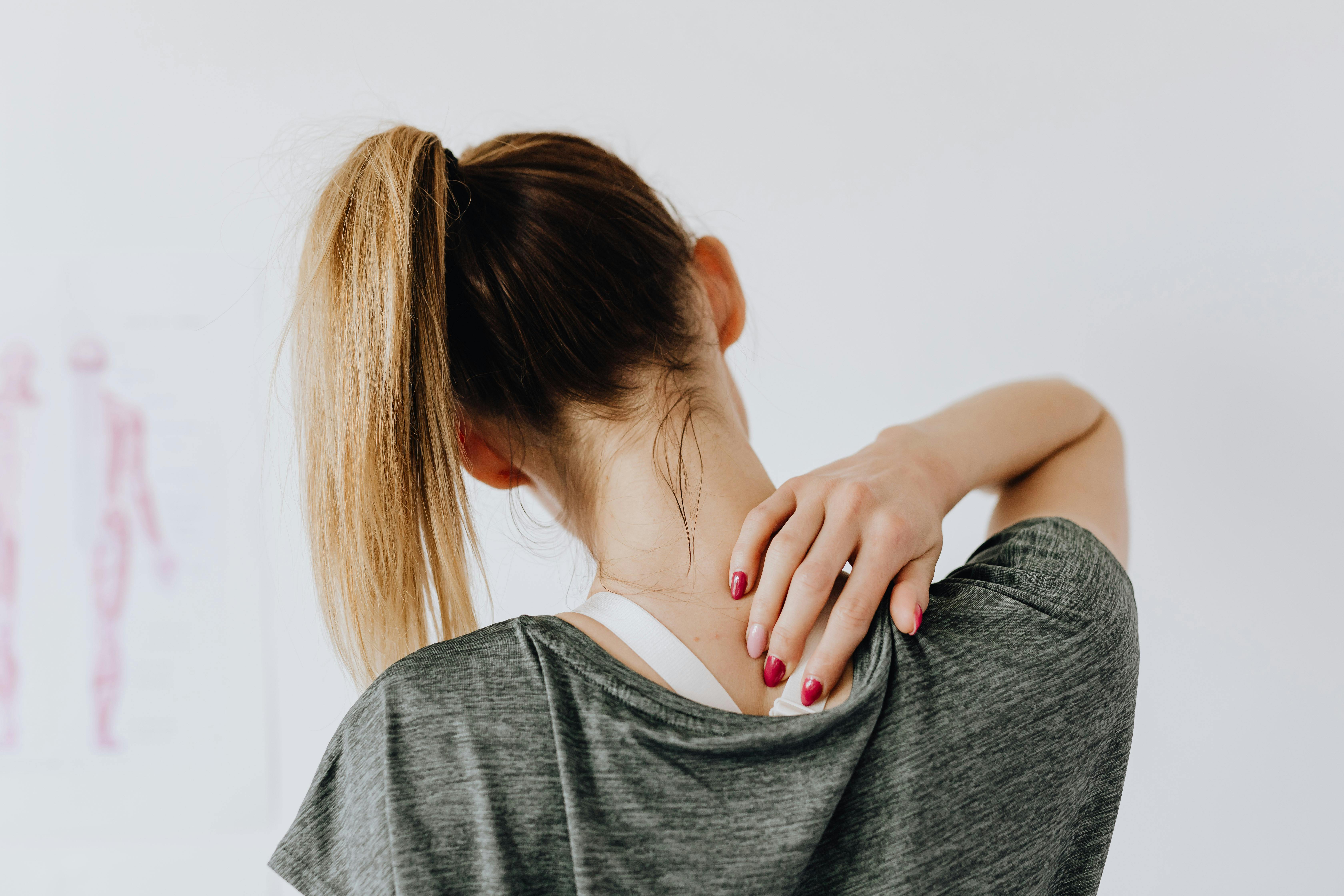 A woman touching the back of her neck | Source: Pexels