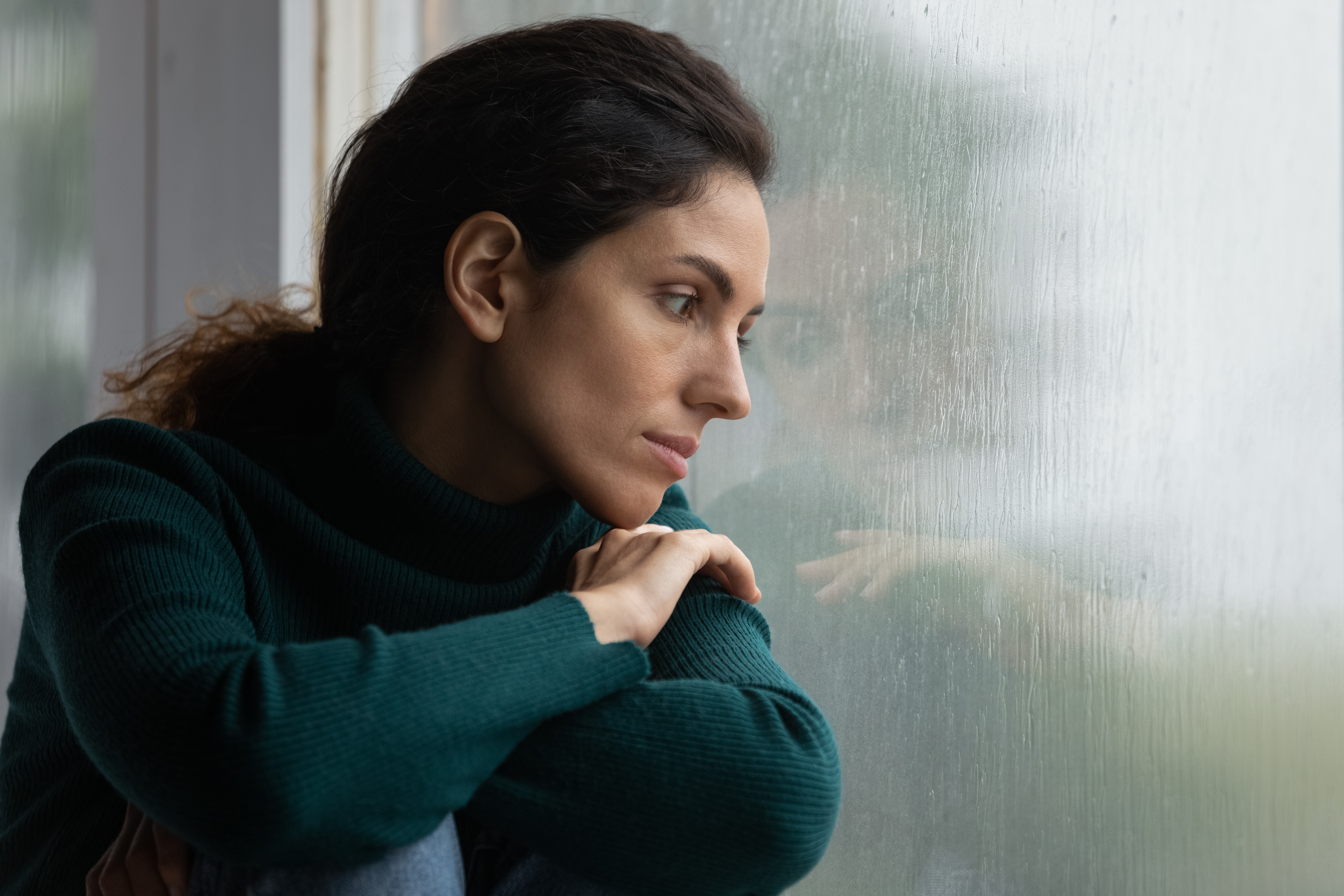 A woman in a melancholic mood looking out the window. | Source: Getty Images