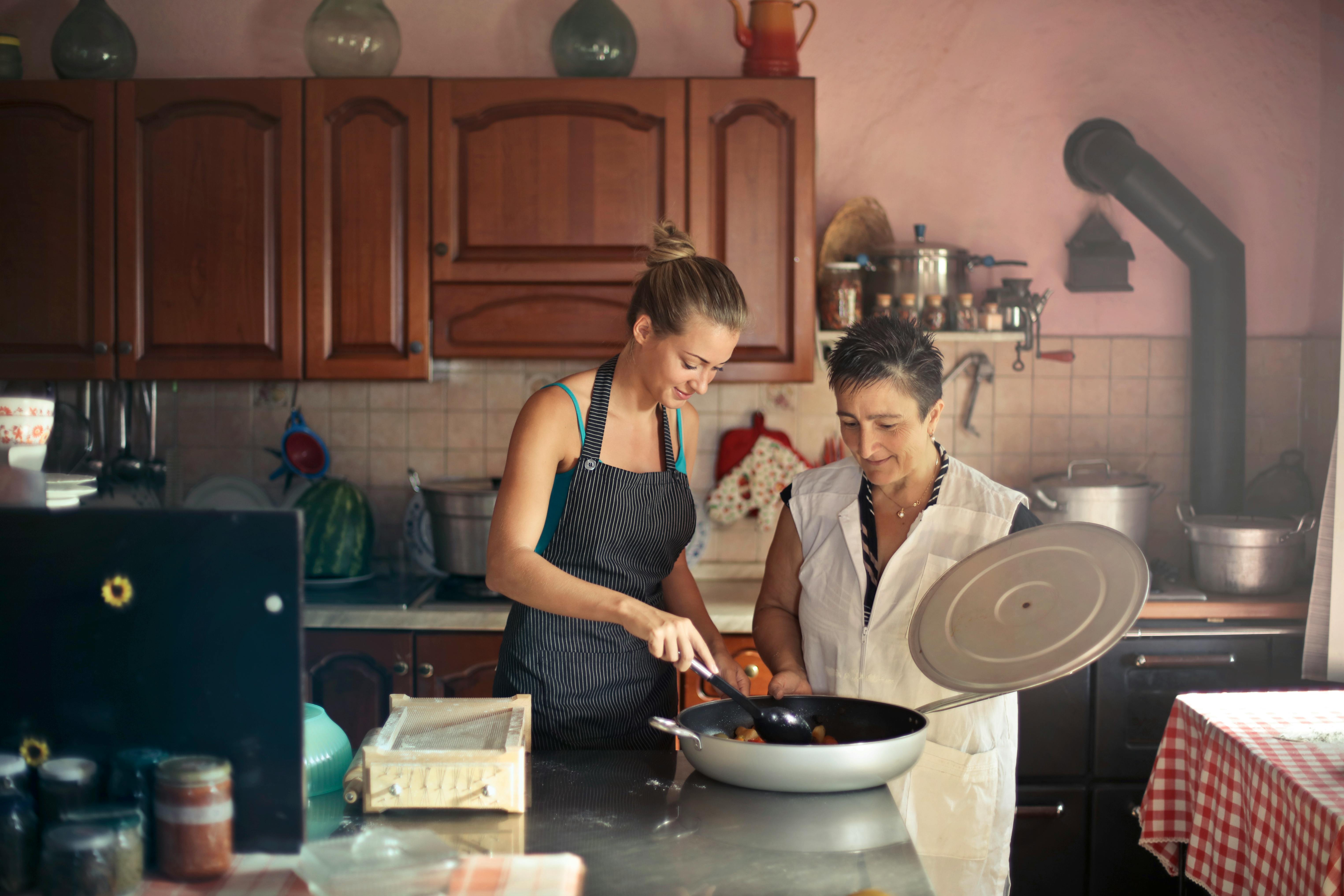 A happy younger woman and an older one working in the kitchen | Source: Pexels