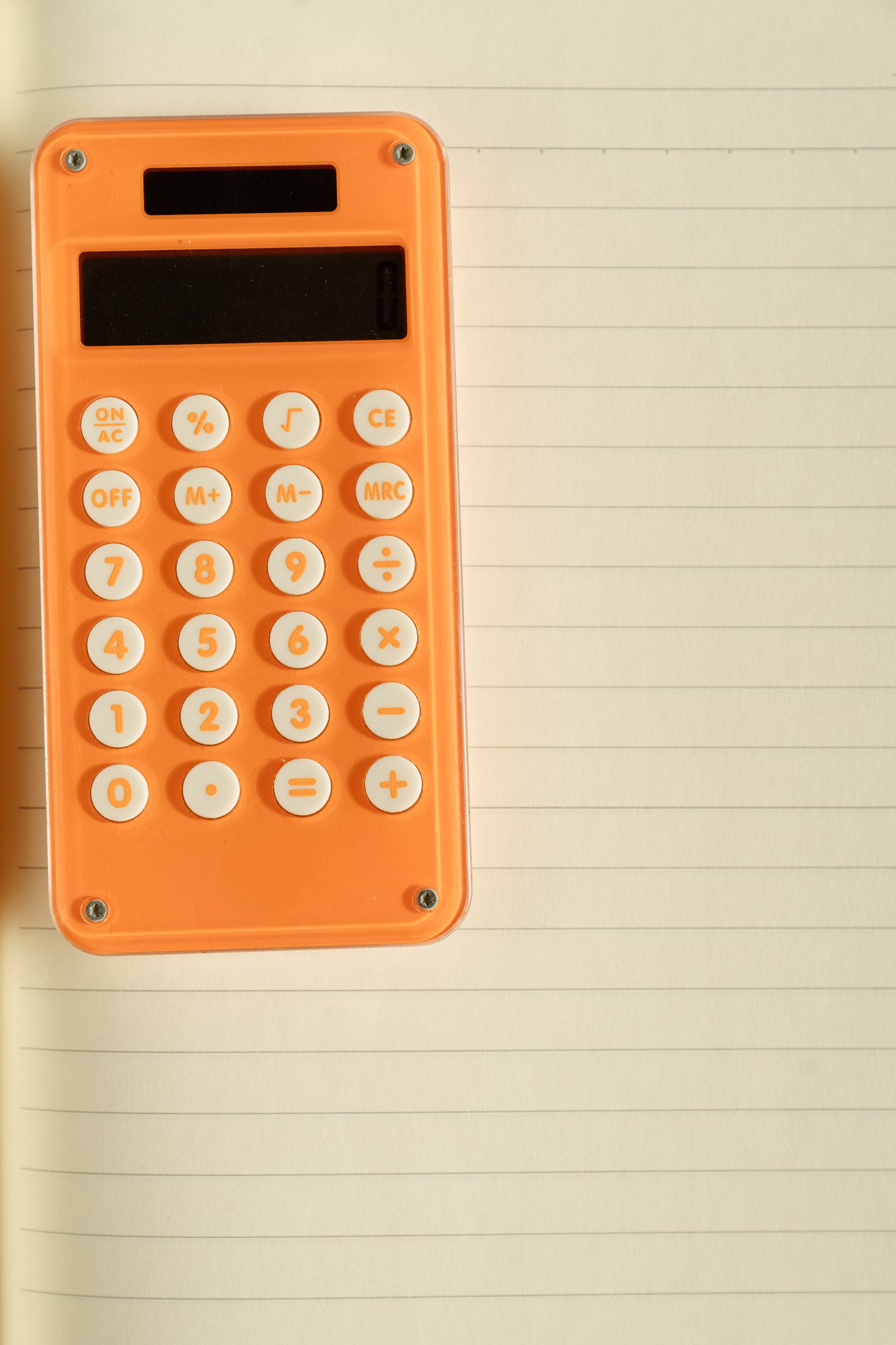 An orange calculator on white paper | Source: Pexels