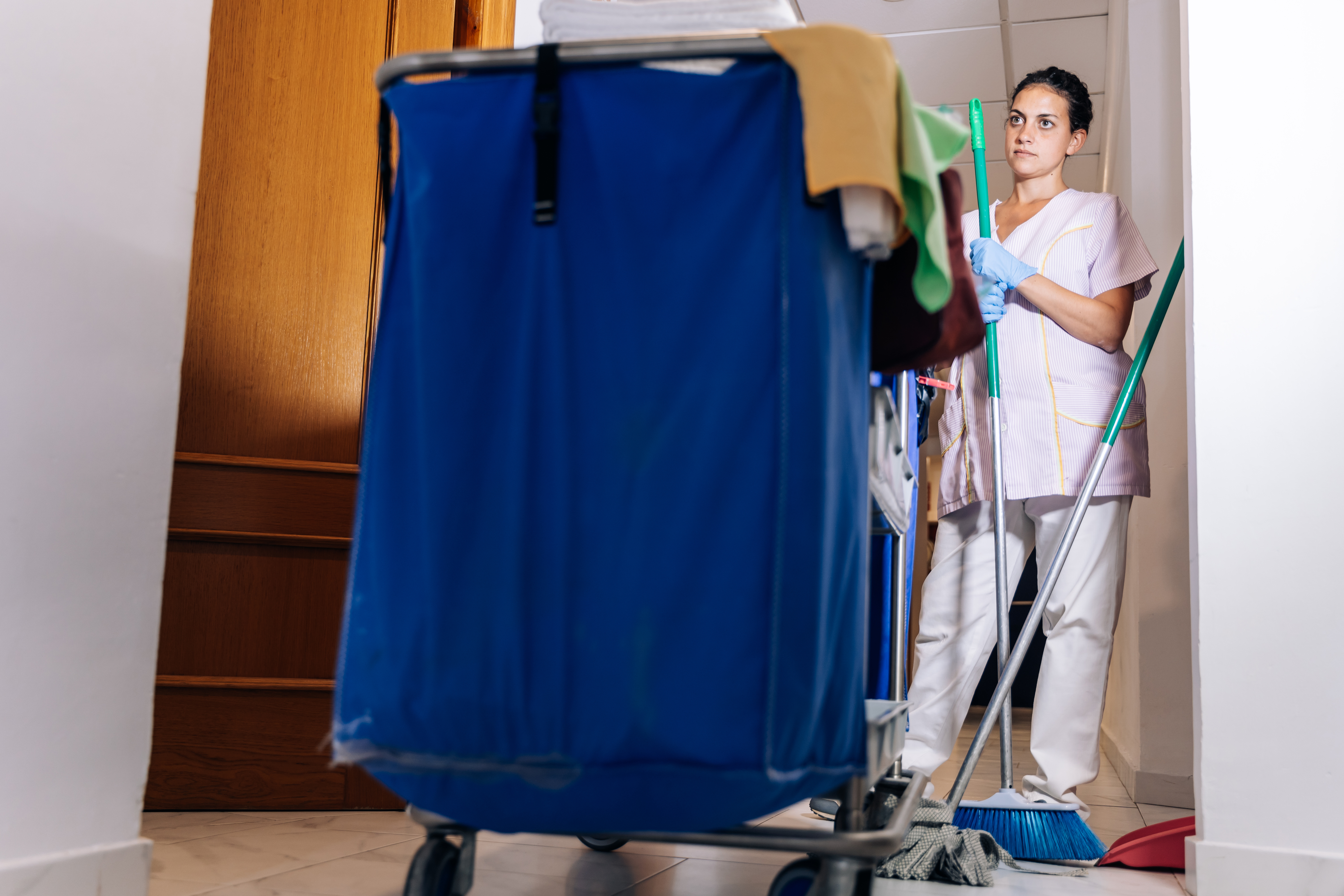 A hotel cleaning employee standing next to a trolley | Source: Shutterstock