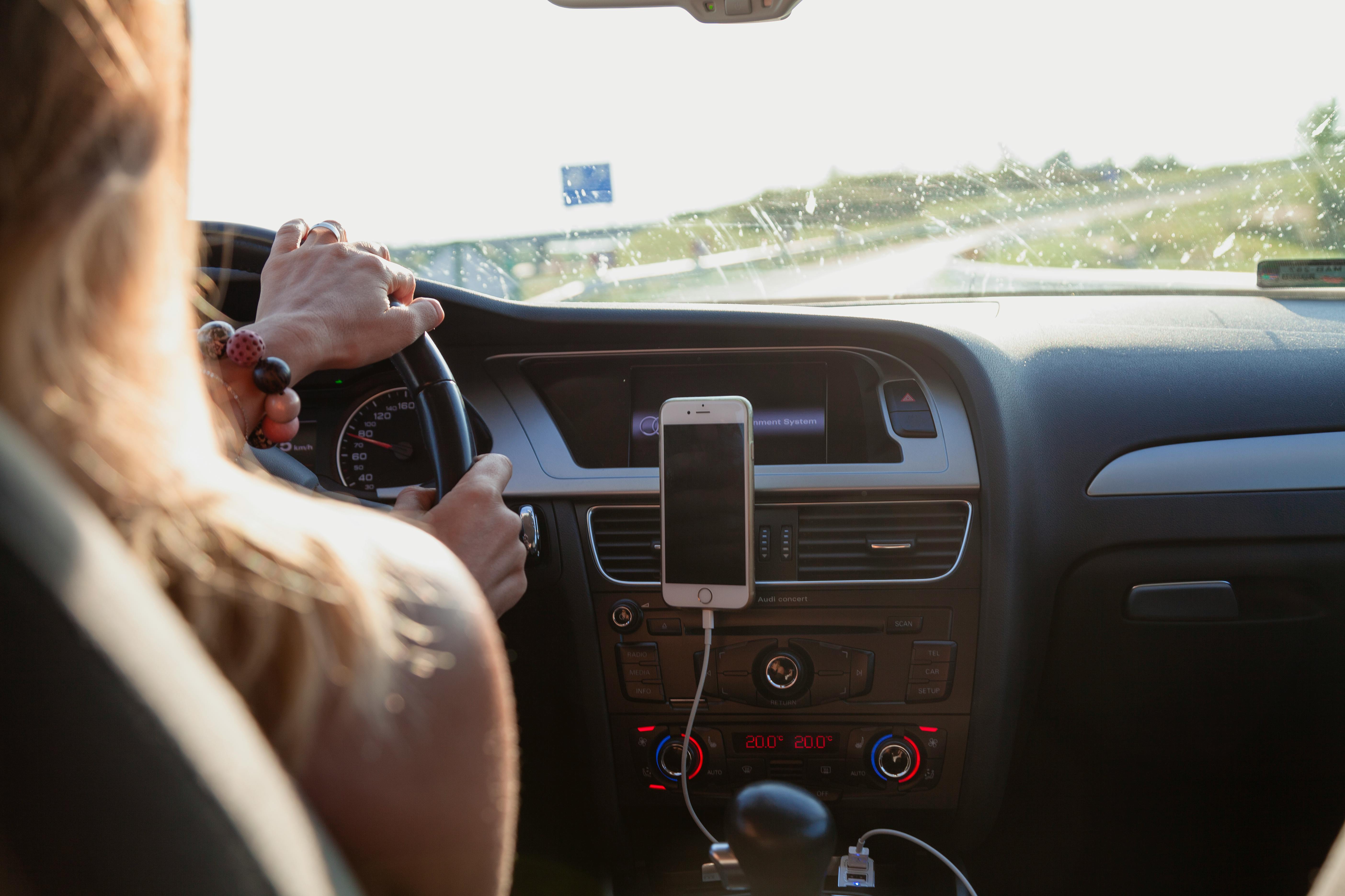 A woman driving with her phone docked in her car | Source: Pexels