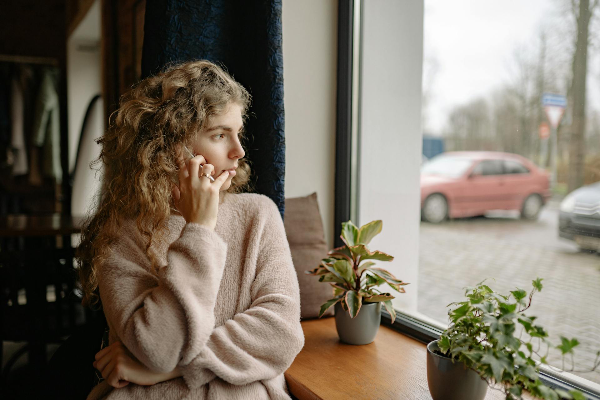 A woman talking on the phone while looking through the window | Source: Pexels