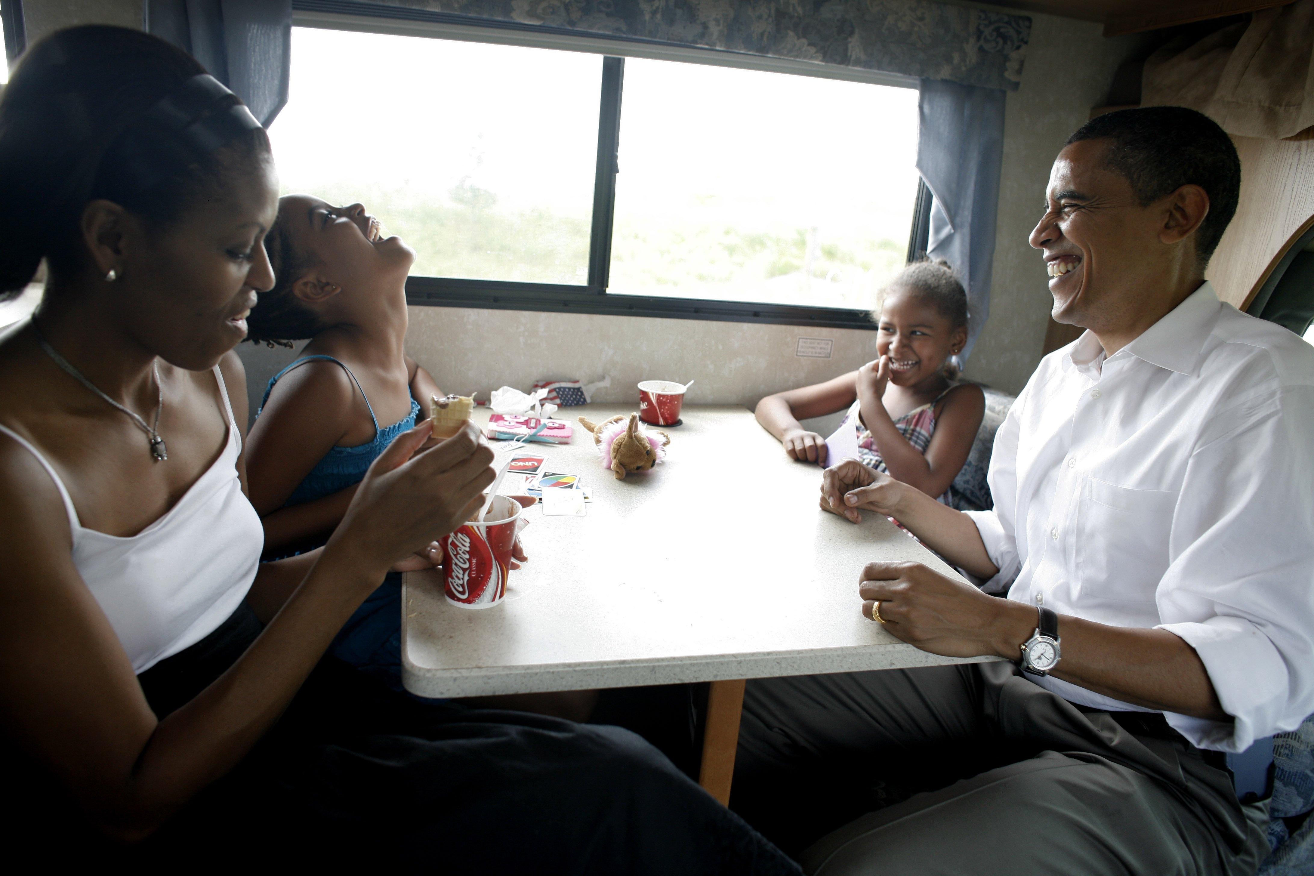 Michelle and Barack Obama playing cards with their daughters in their RV on July 4, 2007. | Source: Getty Images