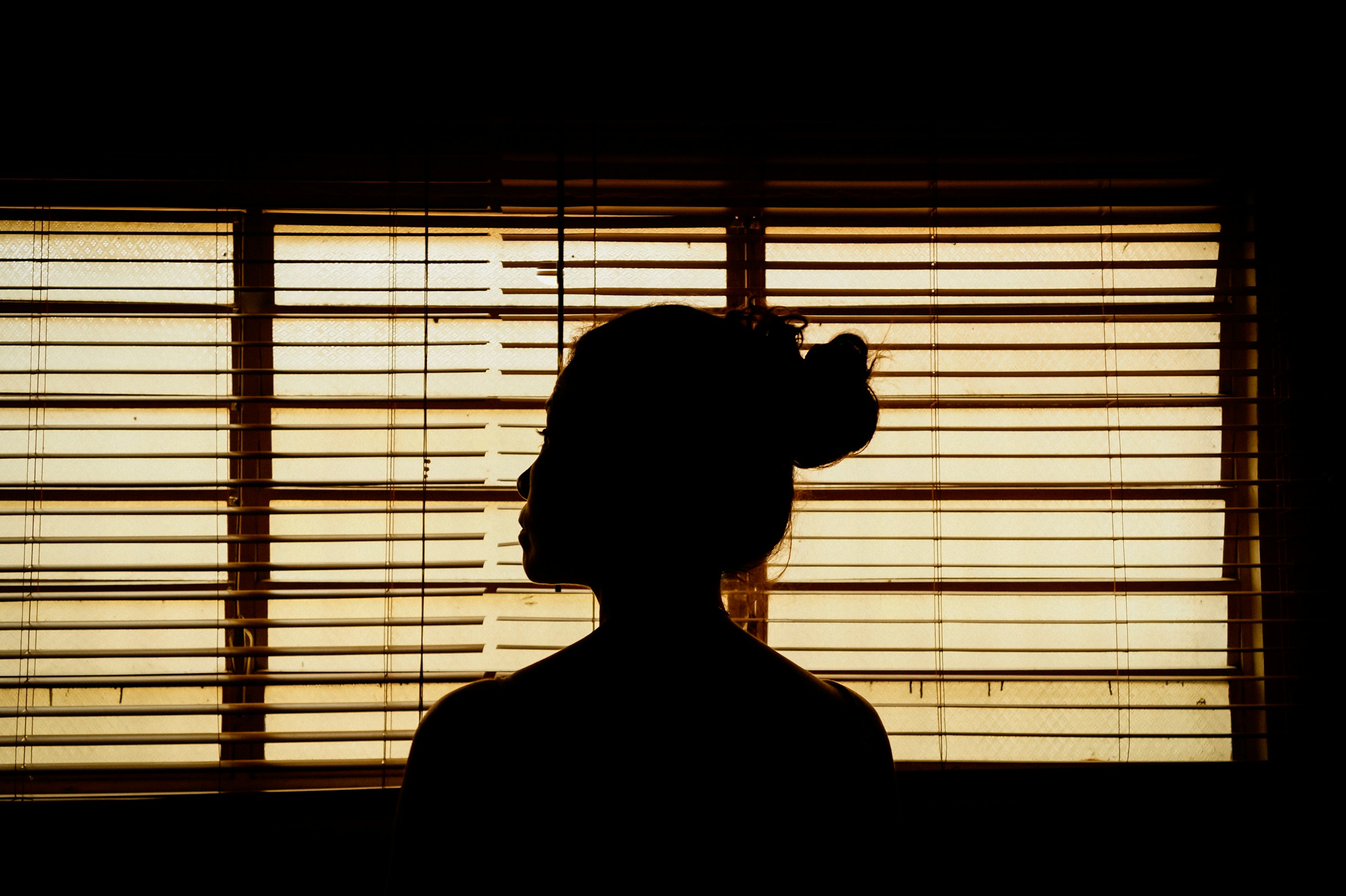 A person hiding behind blinds | Source: Unsplash