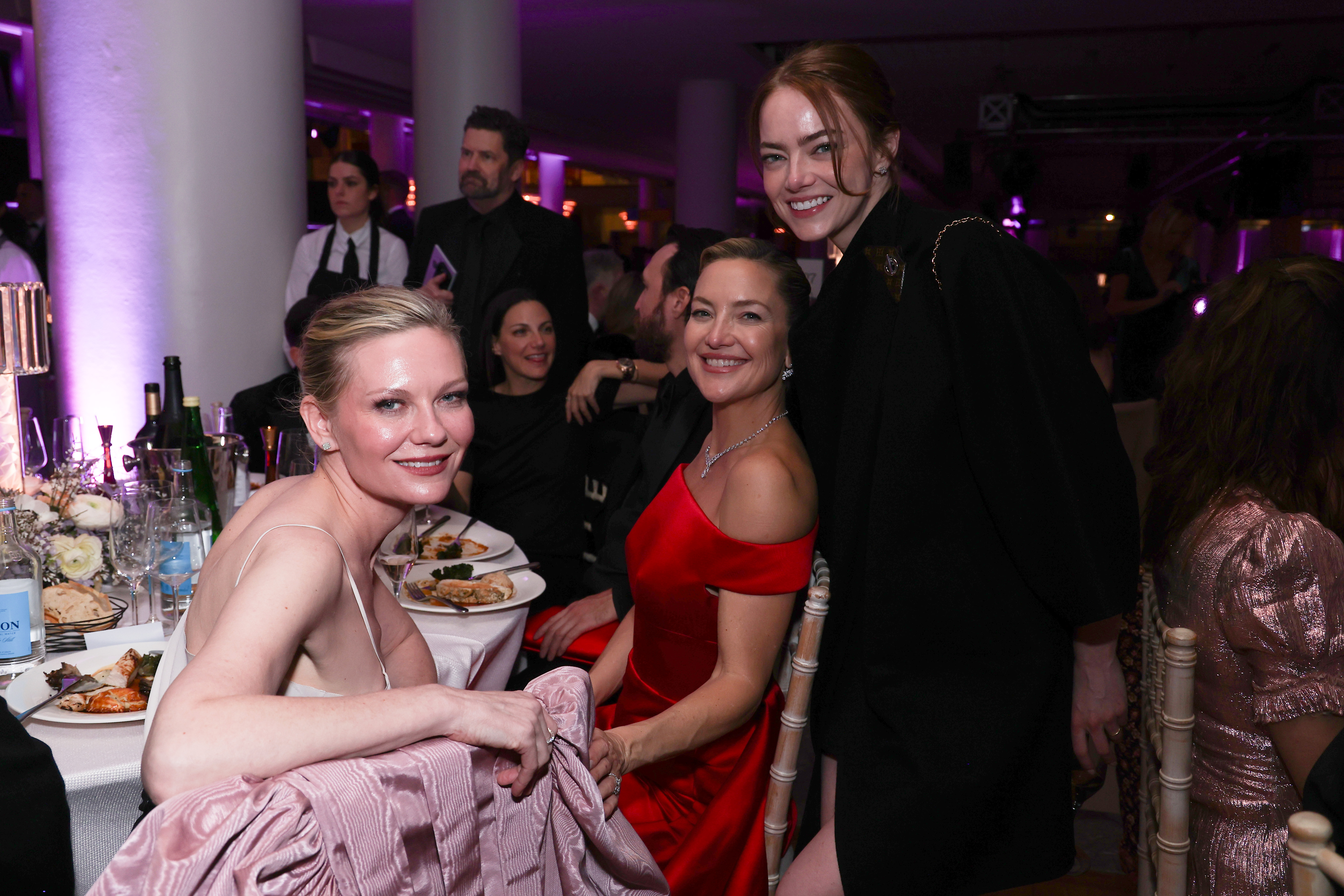 Emma Stone joins Kirsten Dunst and Kate Hudson at their table, leaning in with a bright smile as the trio share a candid snapshot amid dinner and conversation.