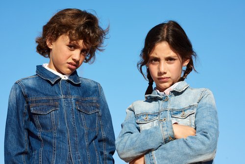 A boy and a girl distrustfully looking at the camera. | Source: Shutterstock.