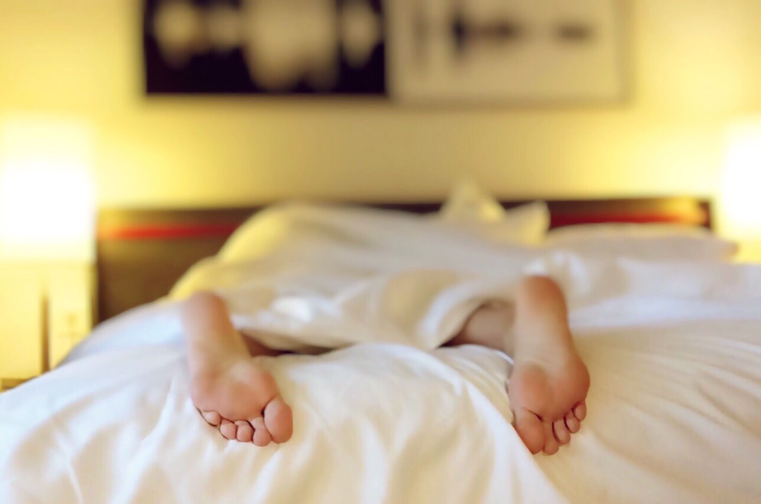 A pair of feet sticking out of a blanket in bed | Source: Pexels