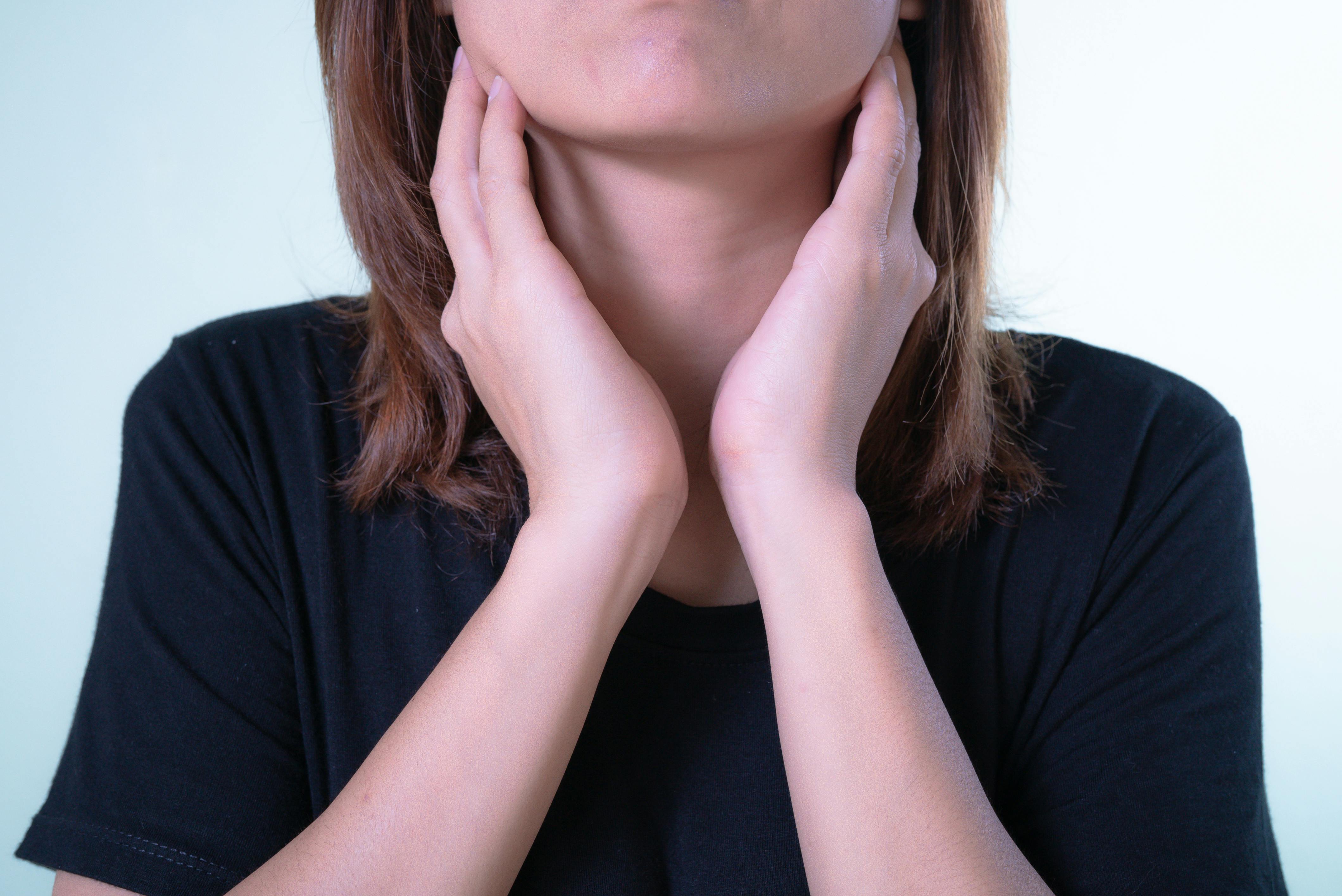 A woman holding her throat area | Source: Pexels