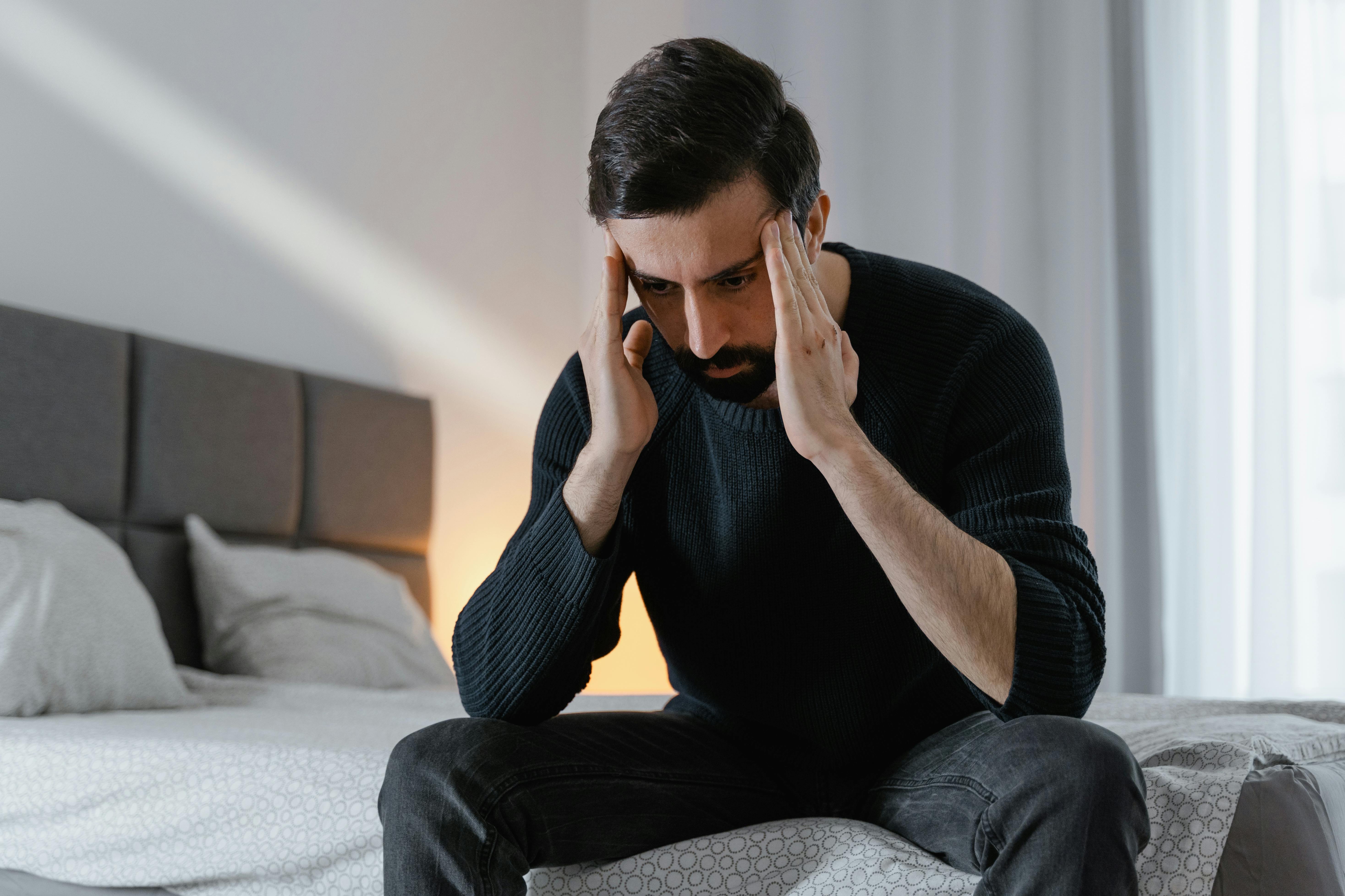 A stressed man sitting on a bed | Source: Pexels