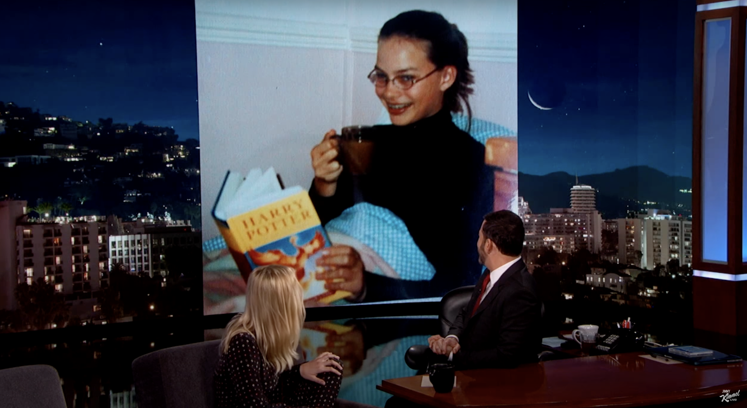 Margot Robbie schaut sich mit Jimmy Kimmel ein altes Bild ihres jüngeren Ichs beim Lesen von "Harry Potter" bei "Jimmy Kimmel Live" im Juni 2016 an. | Source: youtube.com/Jimmy Kimmel Live