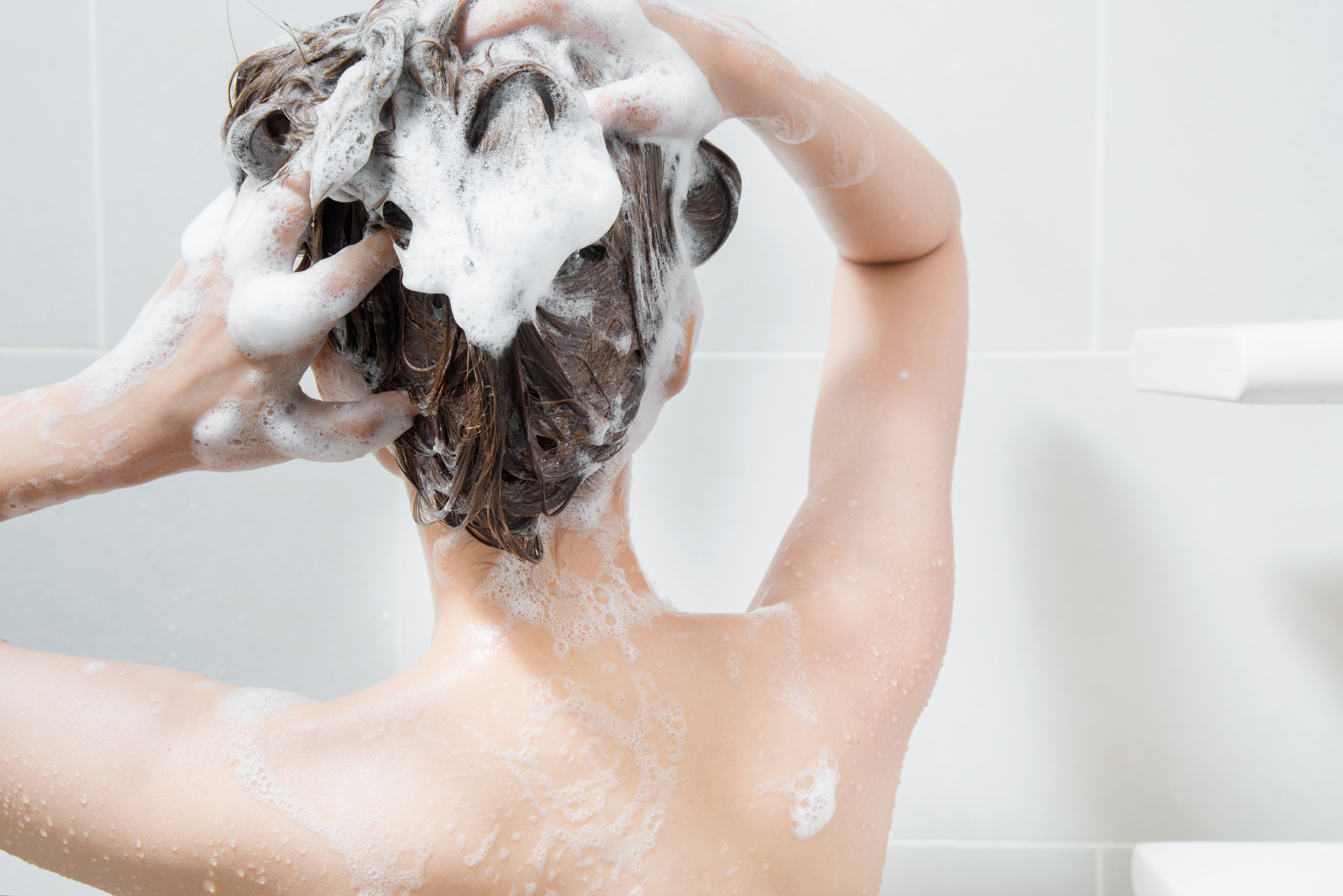 Mujer lavándose el cabello en la regadera. | Foto: Shutterstock