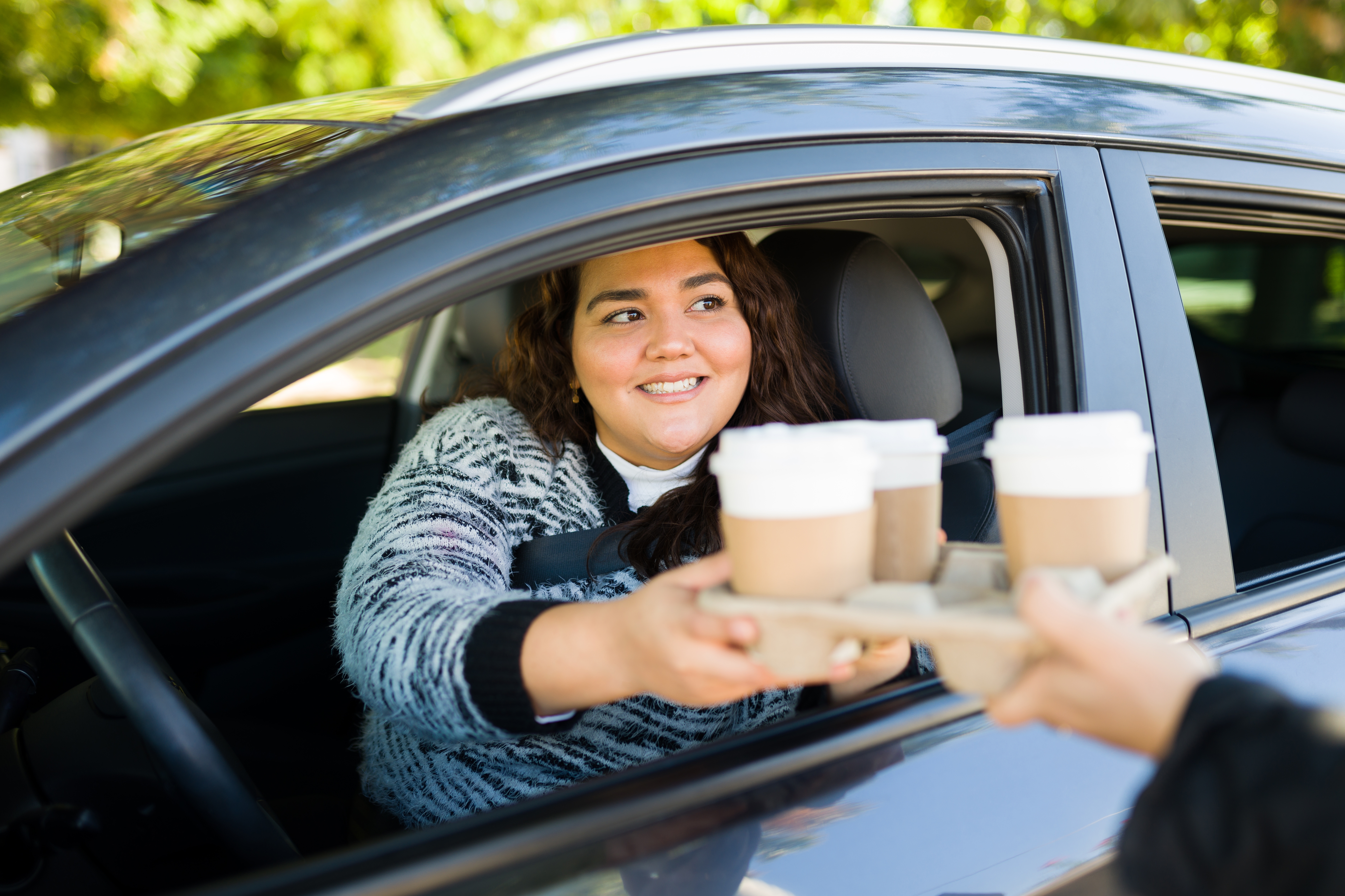Woman driving her car on a through a drive thru buying coffee | Source: Shutterstock
