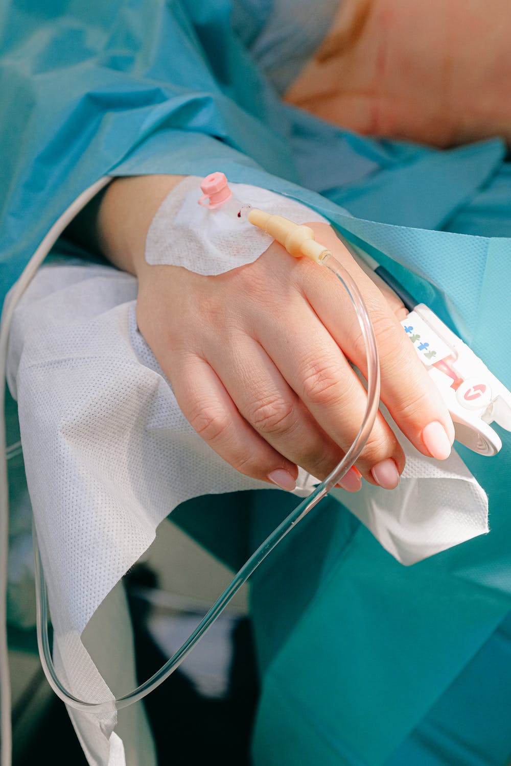 Mujer recostada en una cama de hospital mientras recibe terapia intravenosa. | Foto: Pexels