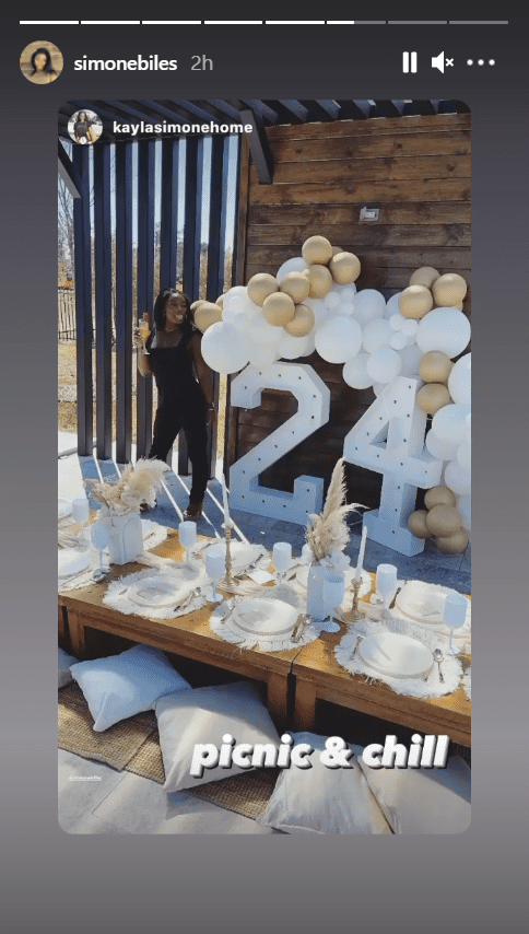 Simone Biles posing next to a balloon arrangement in front of a picnic table for her birthday party| Source: Instagram/simonebiles