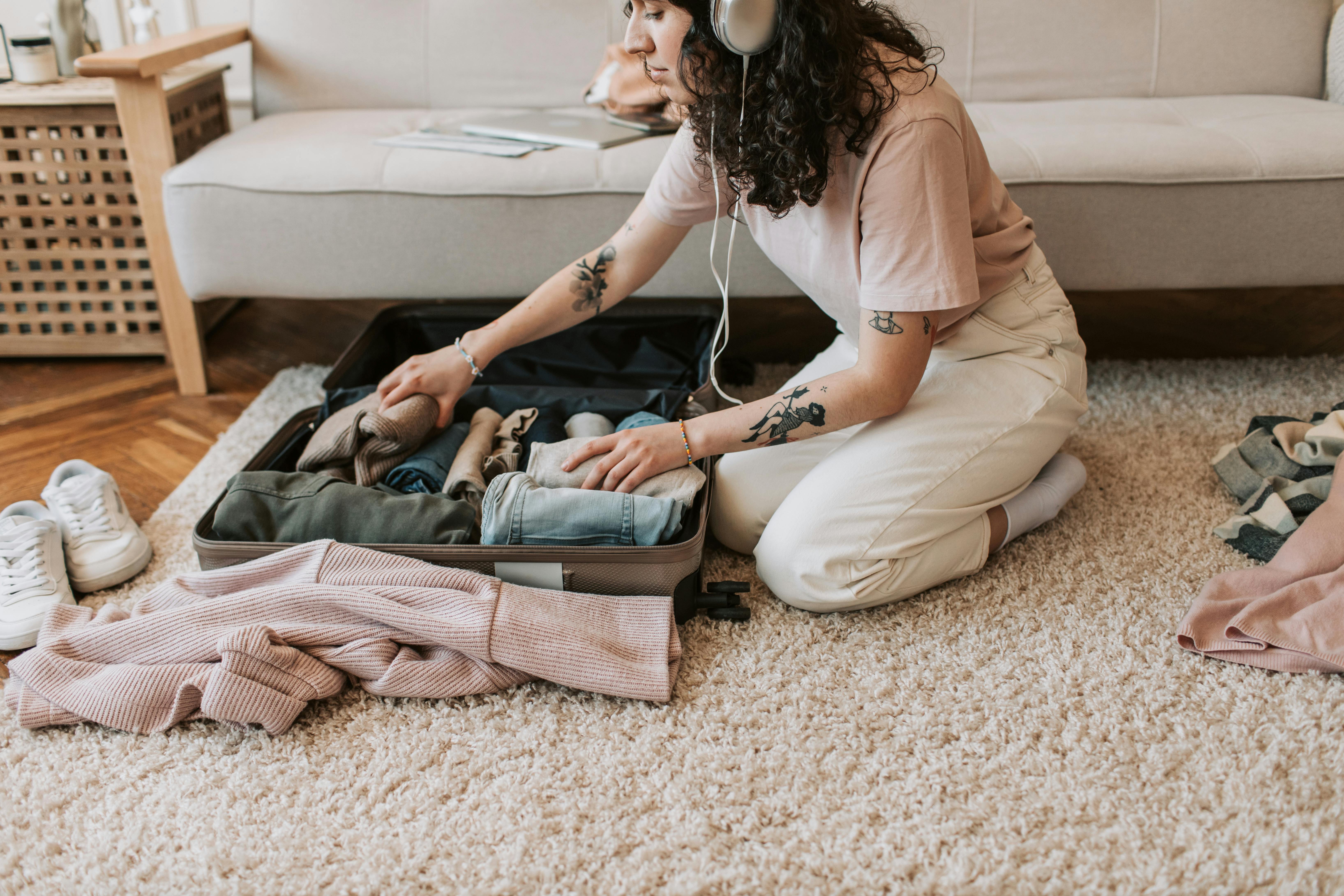 A woman packing her clothes while wearing headsets | Source: Pexels