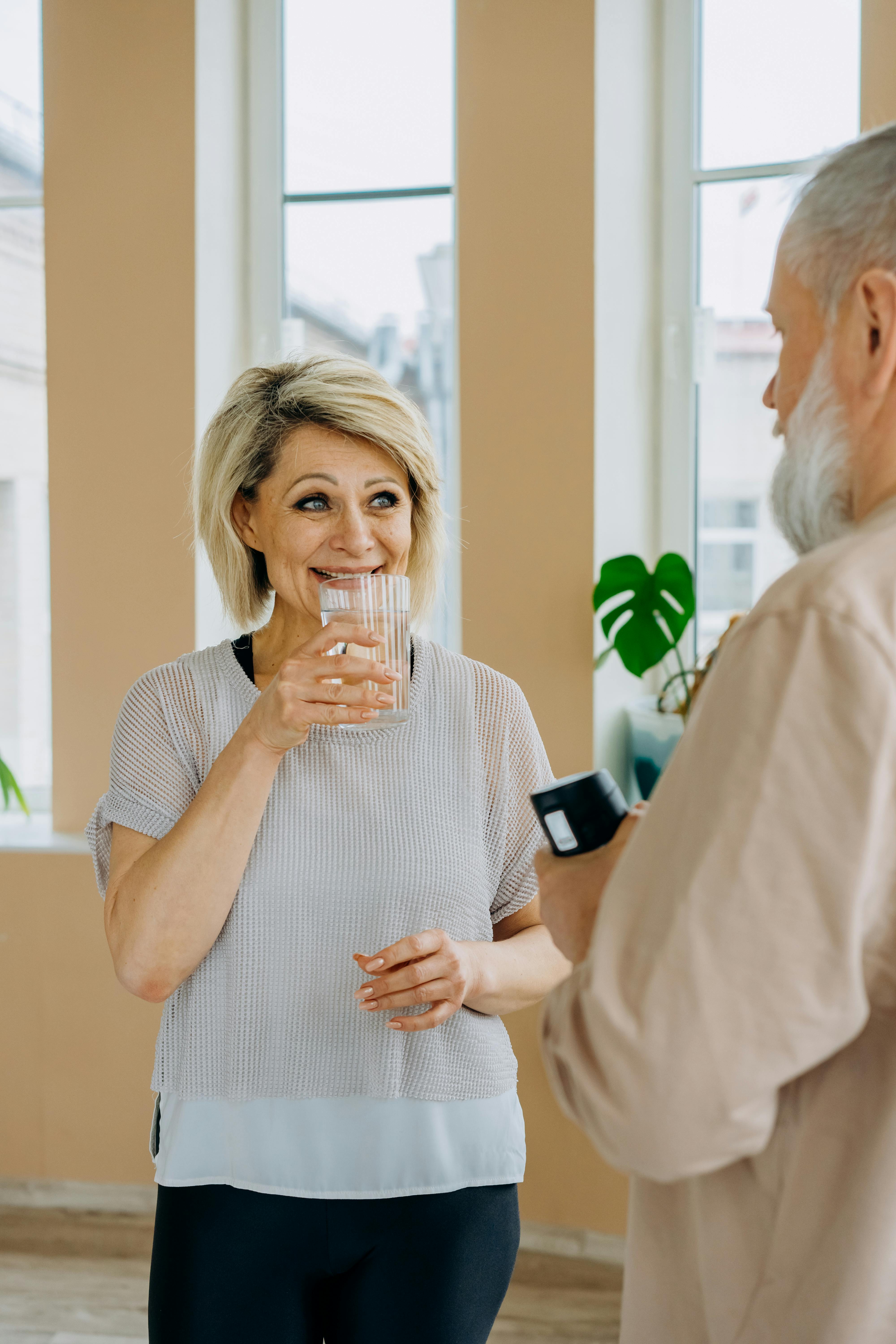 A woman about to take a sip of water while talking to somebody | Source: Pexels