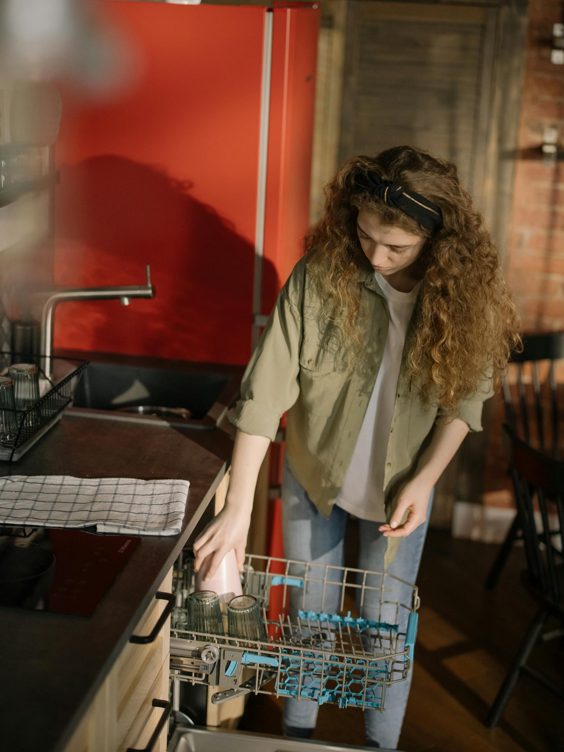 A young woman using a dishwasher | Source: Pexels