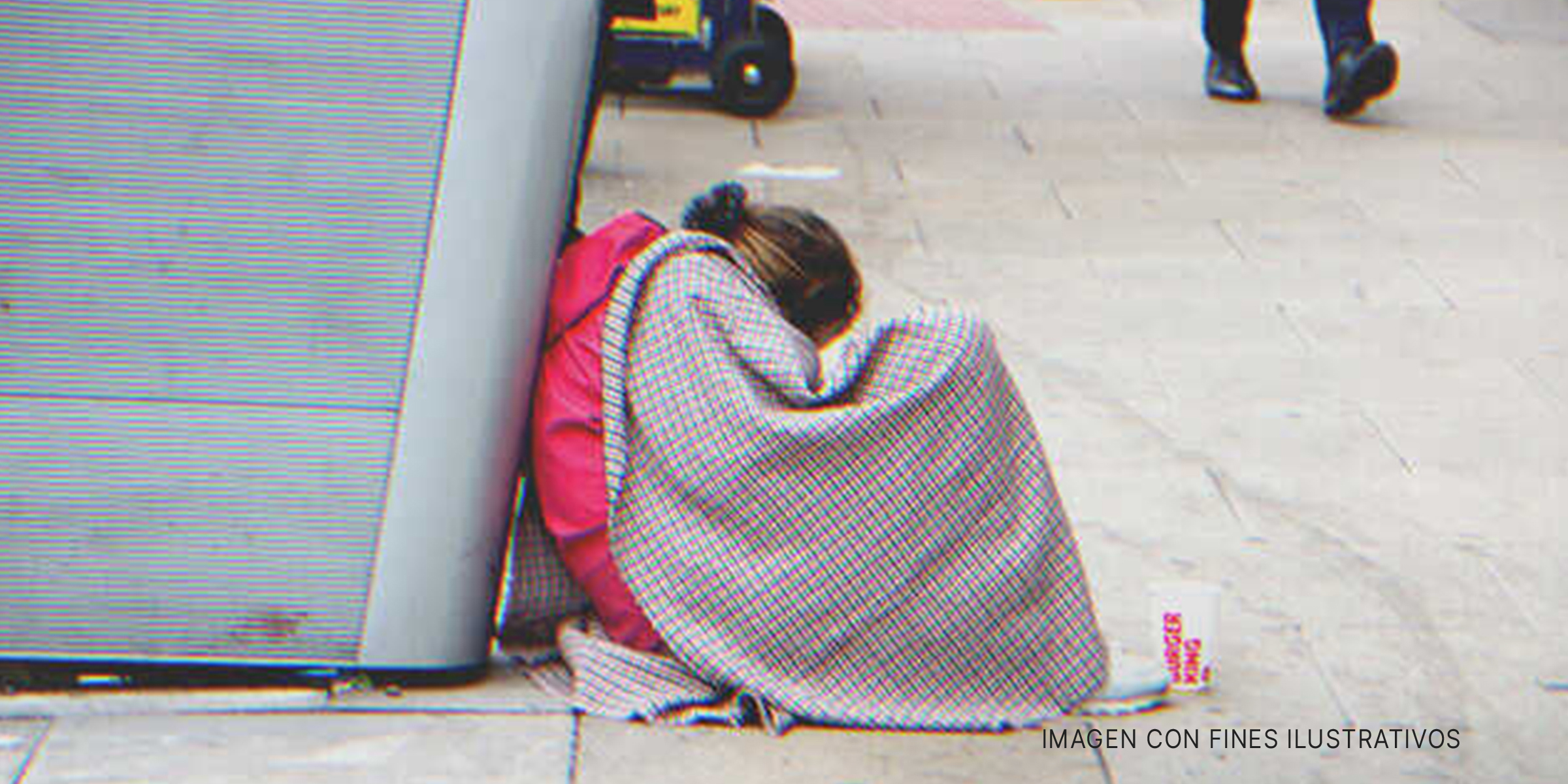 Chica sentada en una acera con una manta. | Foto: Shutterstock